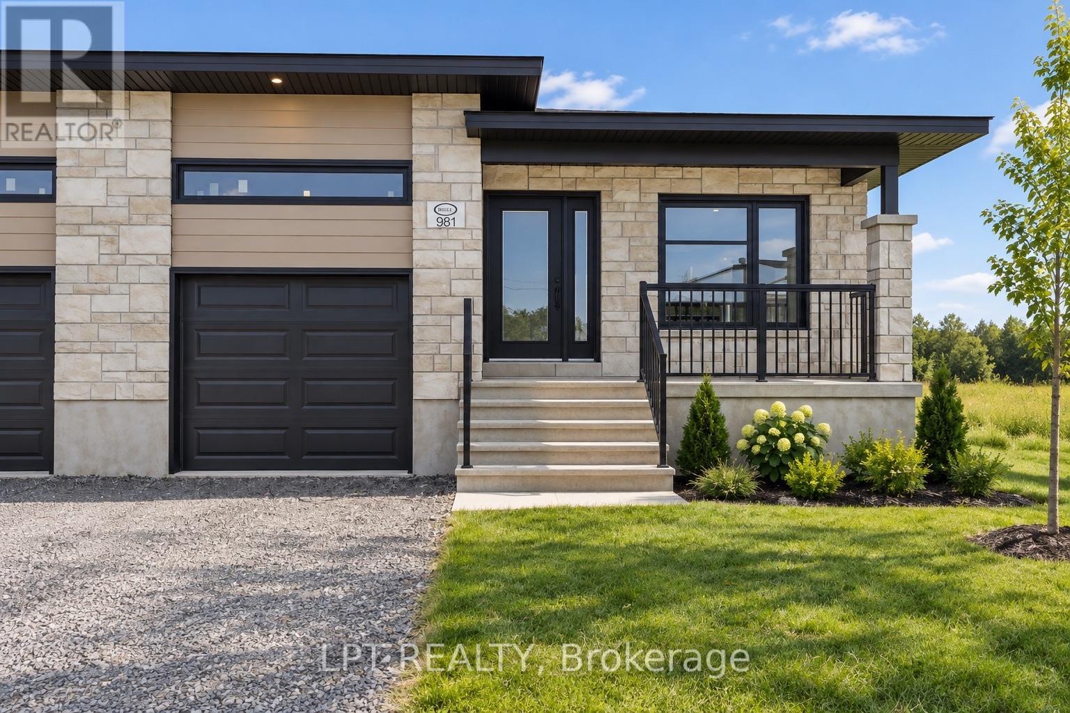 Modern stone-and-siding home with a black garage door, covered porch, and landscaped front lawn.