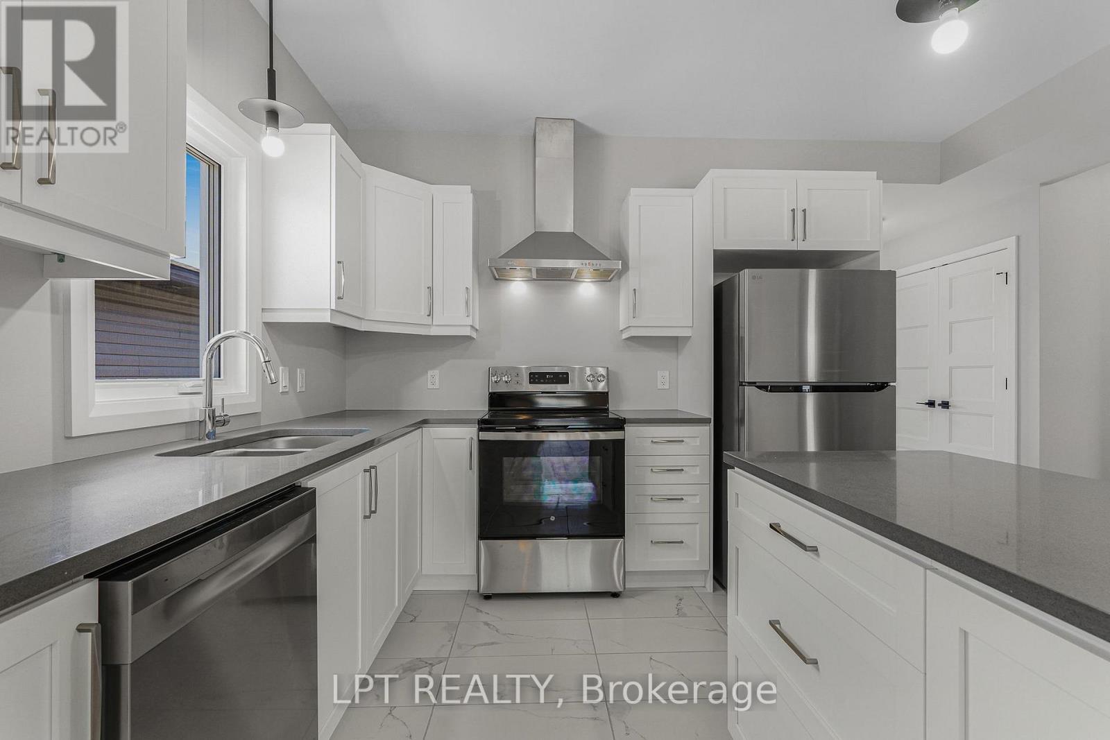 Bright kitchen with white cabinetry, gray counters, stainless appliances, and a central island.