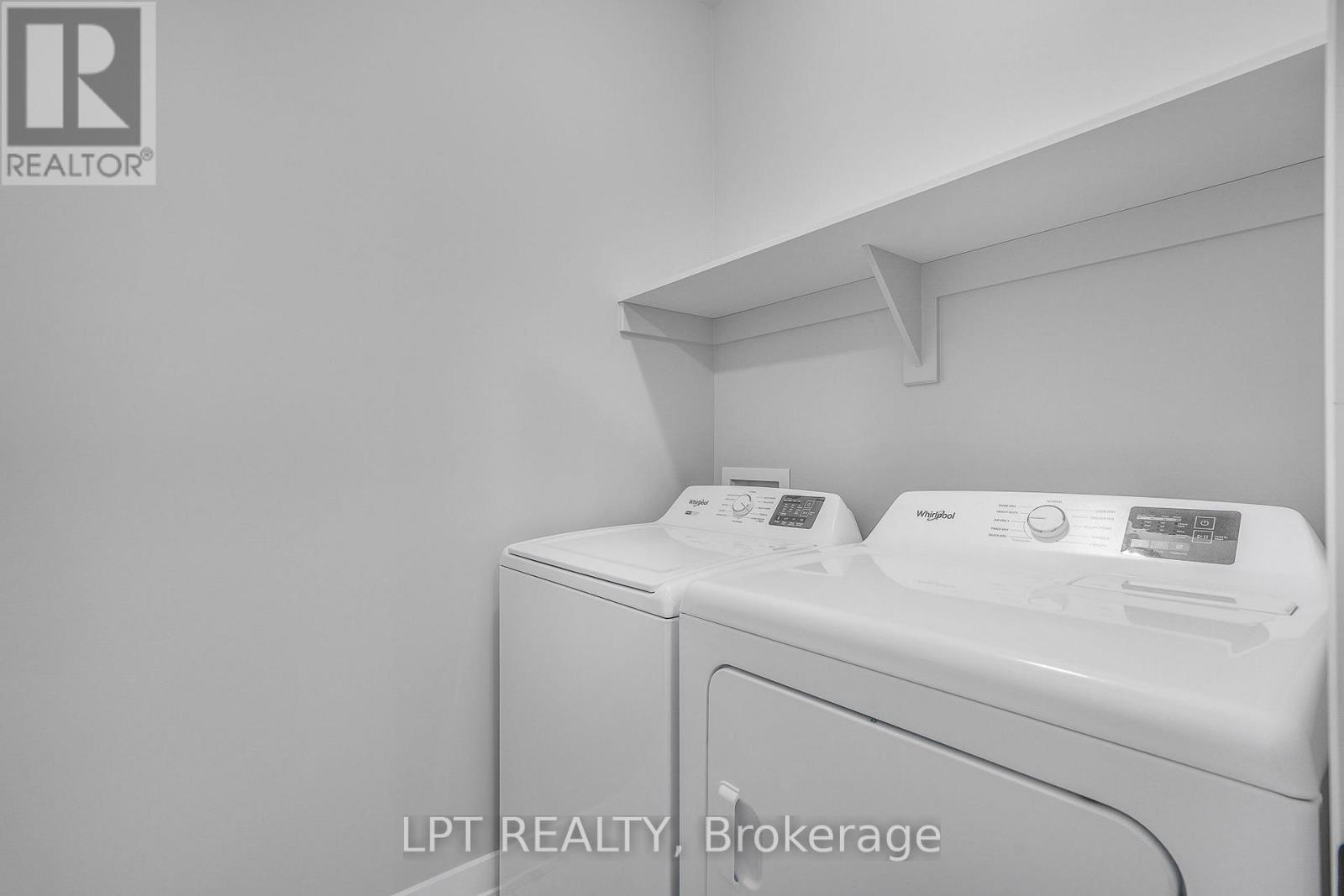 Laundry room with a white washer and dryer beneath a wall-mounted shelf.