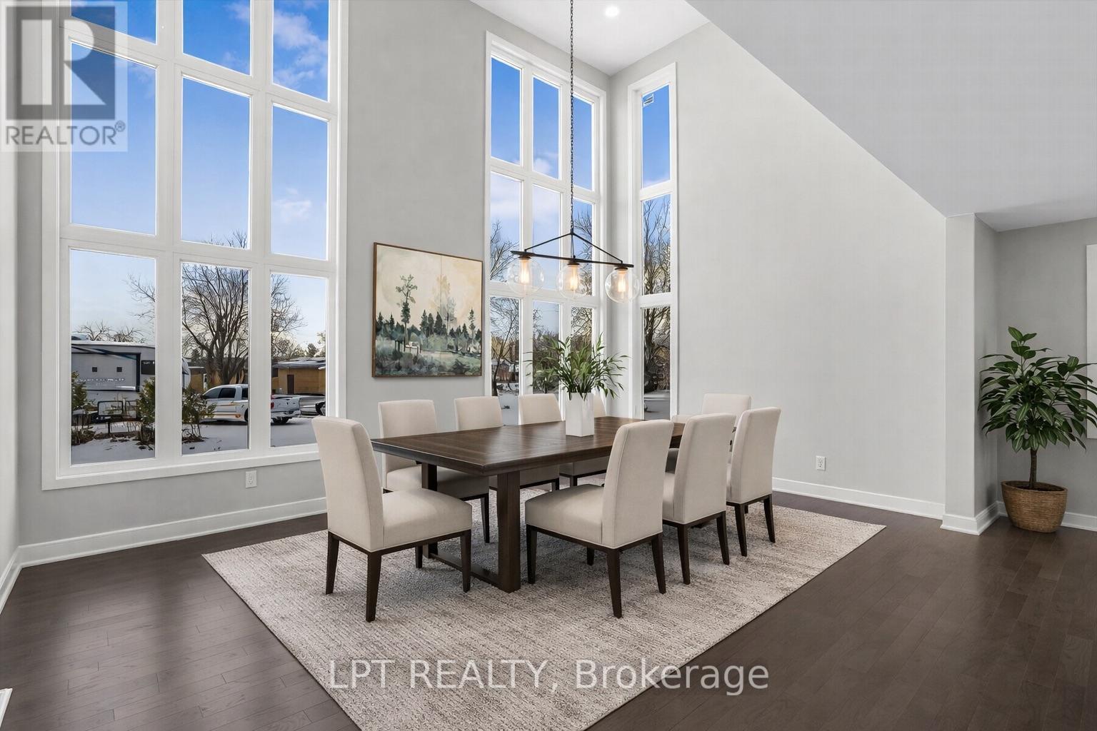Furnished dining room with a dark wood table, tall windows, and a three-light pendant.