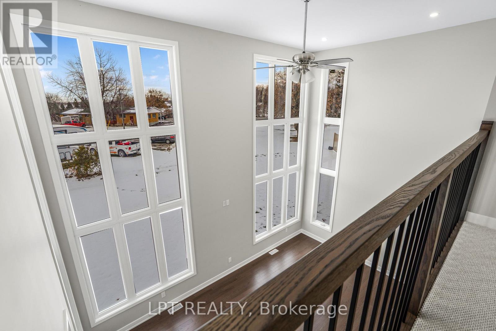 Upper landing overlooking a tall foyer with expansive windows and a dark wood railing.