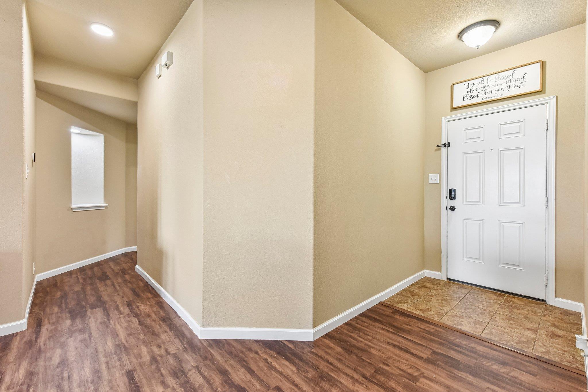 Entryway with a white front door, tan tile threshold, and dark wood-look flooring.