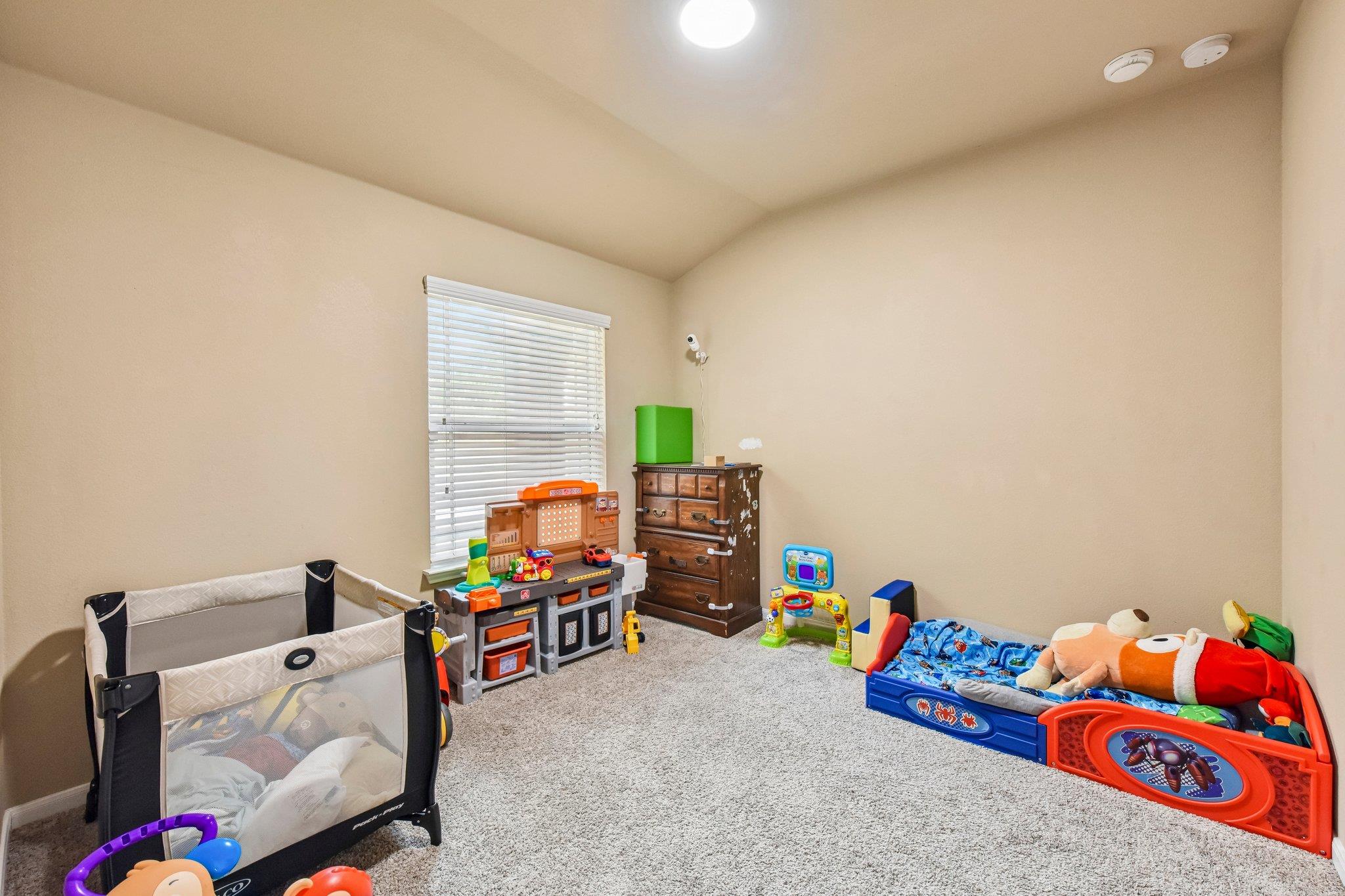 Nursery with a playpen, colorful toys, and a child-sized bed.