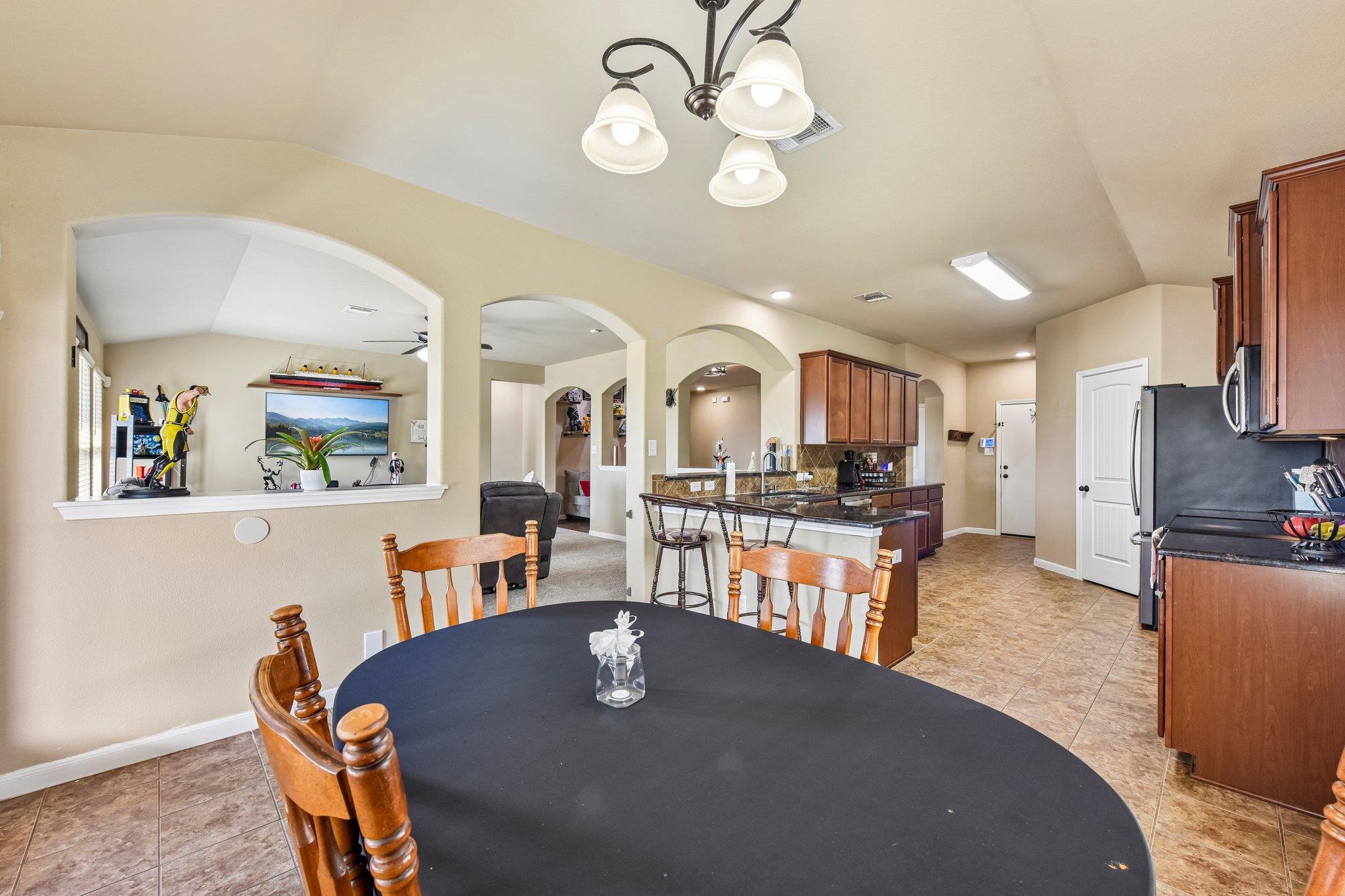 Open kitchen and dining area with arched openings, a central island, and a large oval dining table.