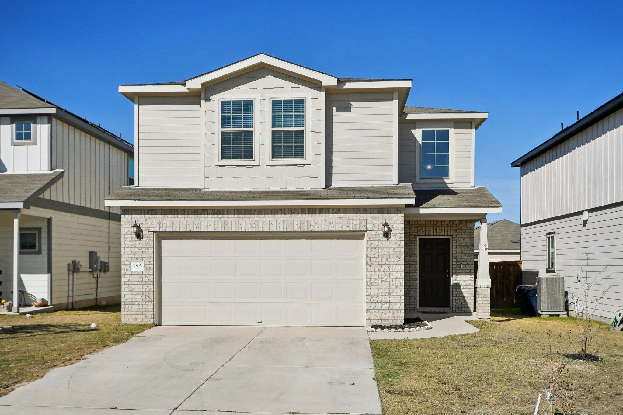 Two-story light-colored home with white brick, a wide garage, and house number 185.