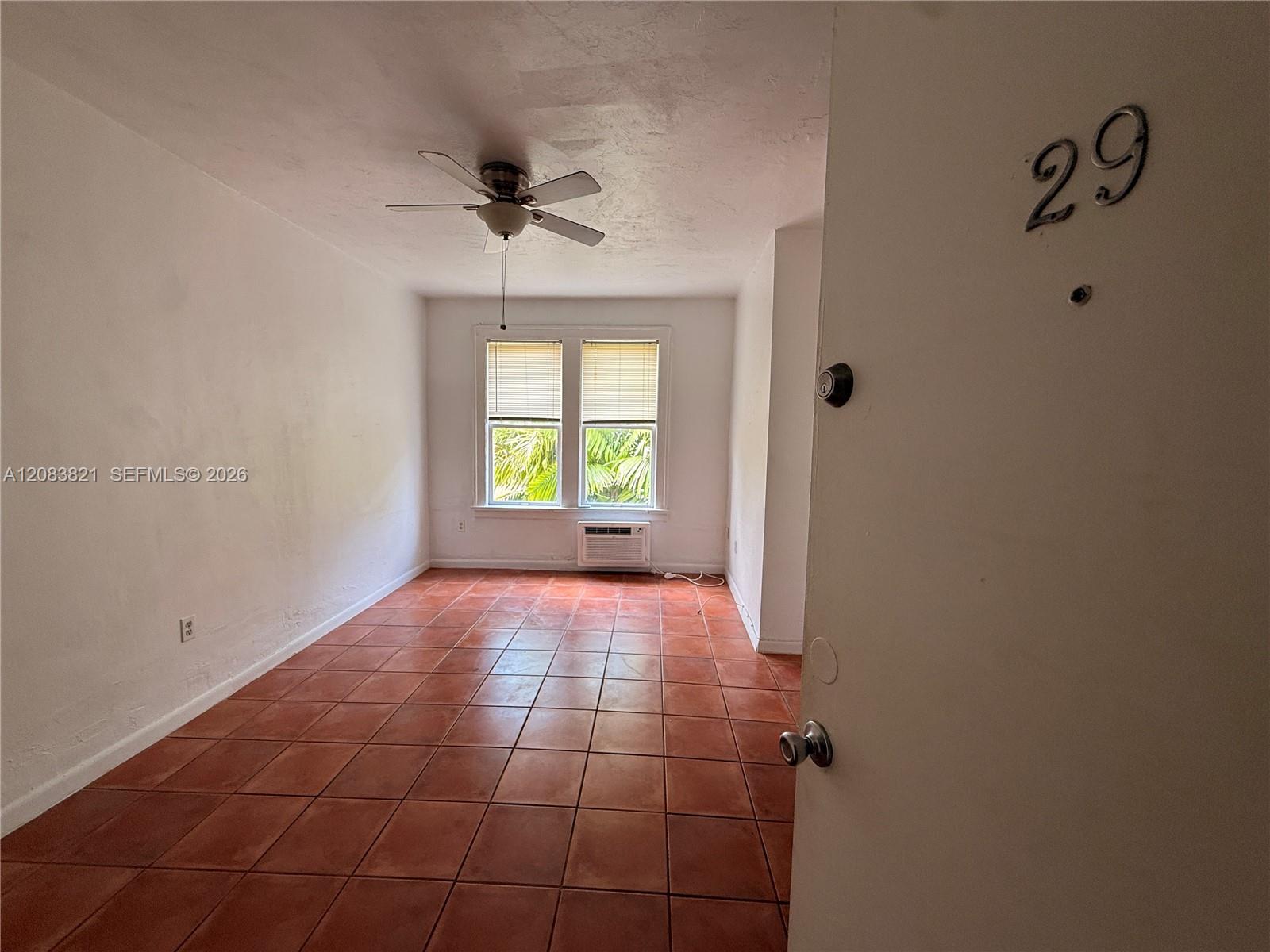 Vacant room with terracotta tile, ceiling fan, and twin windows with blinds.