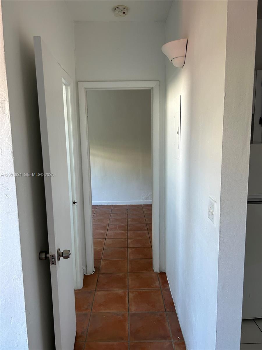 Interior hallway with terracotta tile floors and open doorways.