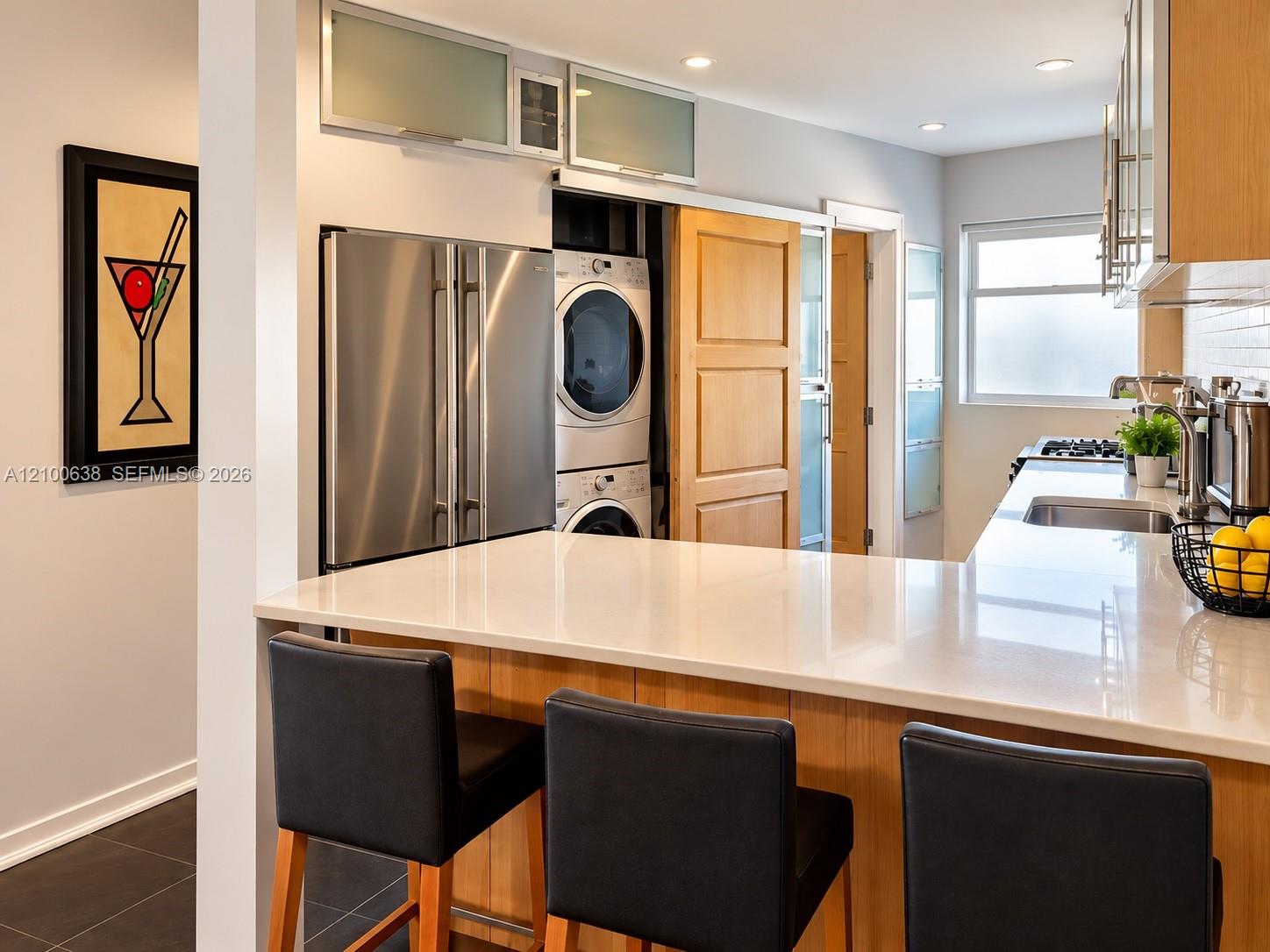 Modern kitchen with a white island, stainless-steel appliances, and built-in washer and dryer.