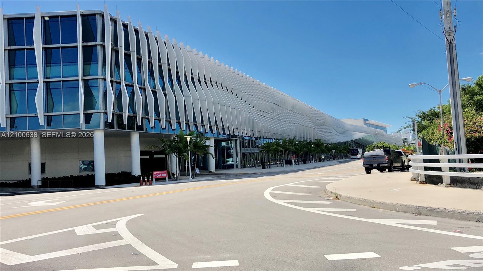 Modern glass-fronted building with repeating white fins along a Miami Beach street.