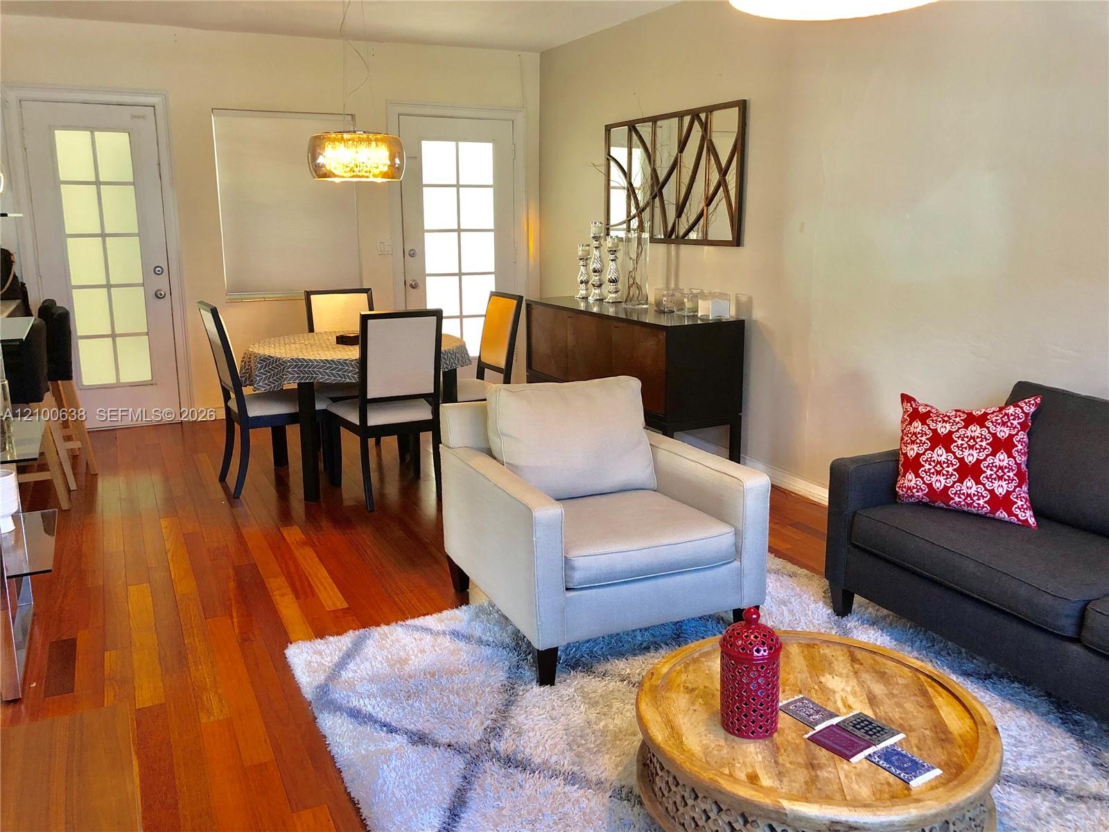Living and dining area with hardwood floors, upholstered chairs, and a round wooden coffee table.