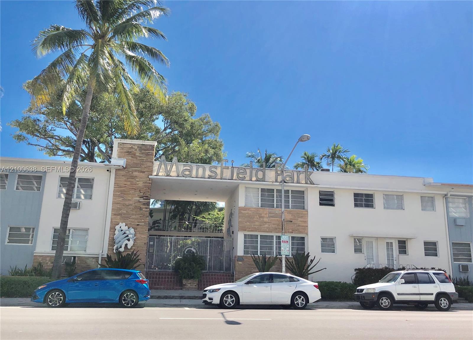 Mansfield Park apartment building with a stone-clad entrance and palm trees.