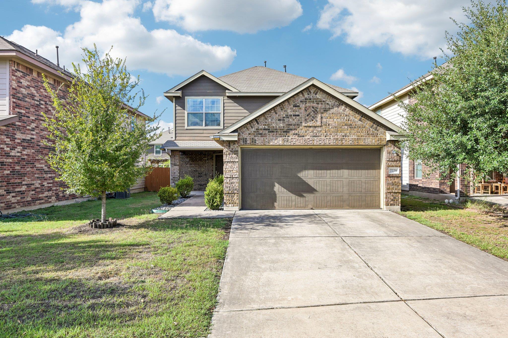 Two-story brick-and-siding house with a wide double garage and concrete driveway.