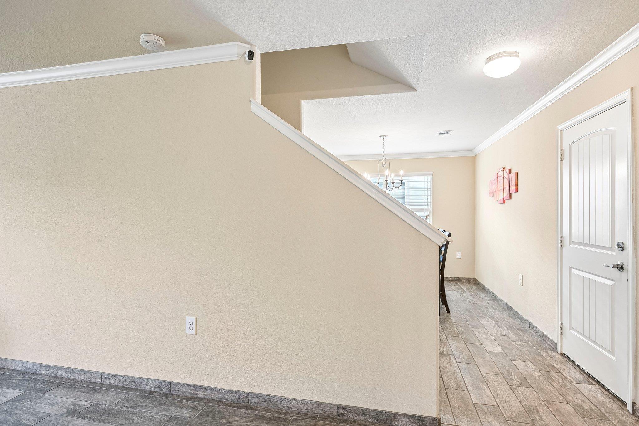 Entry hall with gray tile flooring, a white front door, and a staircase with white railing.