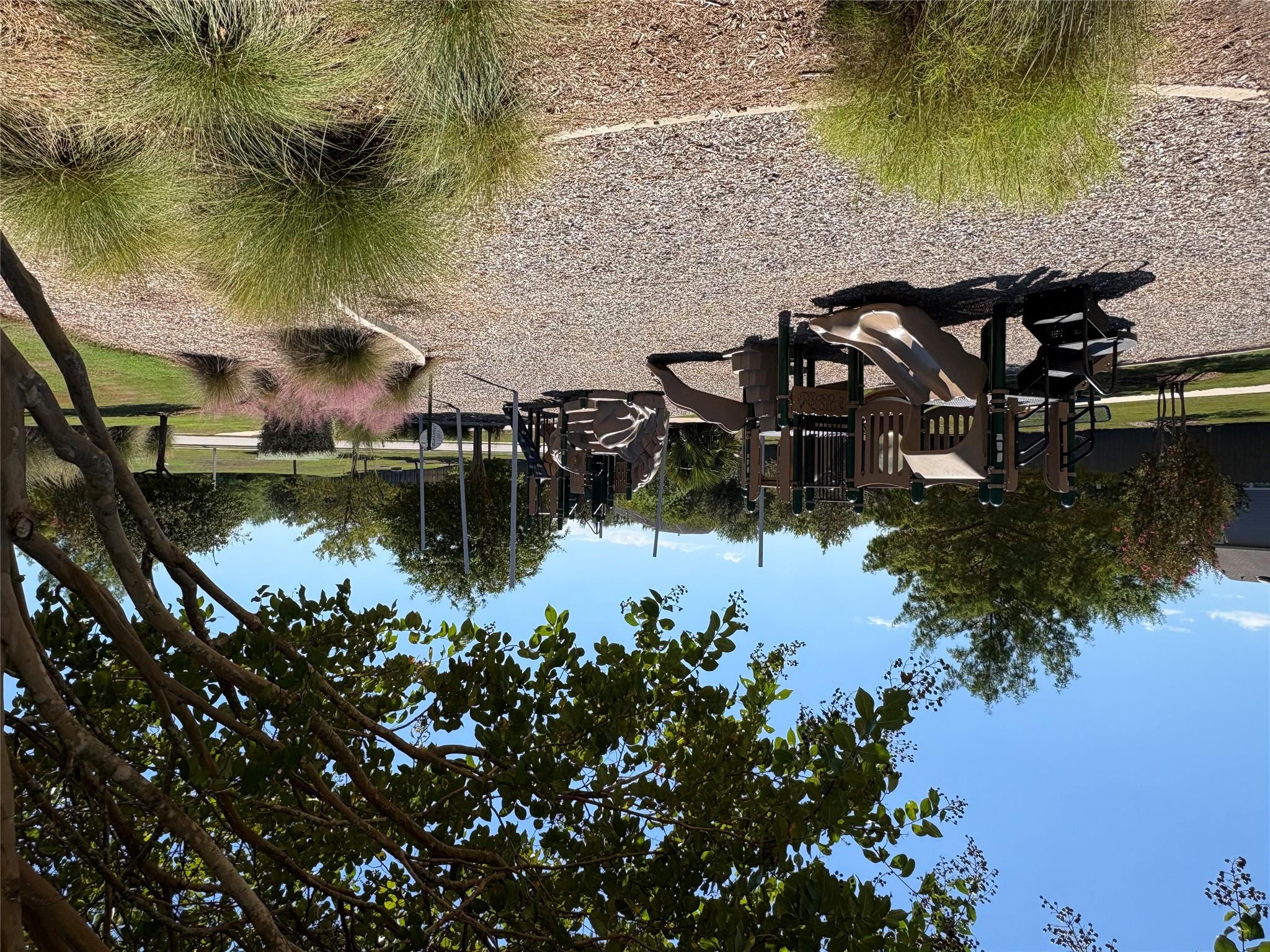 Neighborhood playground with slides and play structures beneath mature trees.