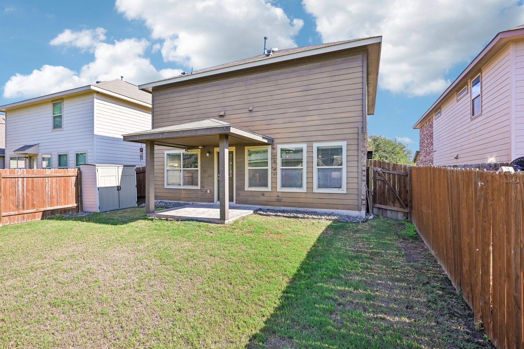 Two-story home with a covered patio overlooking a fenced grassy backyard.