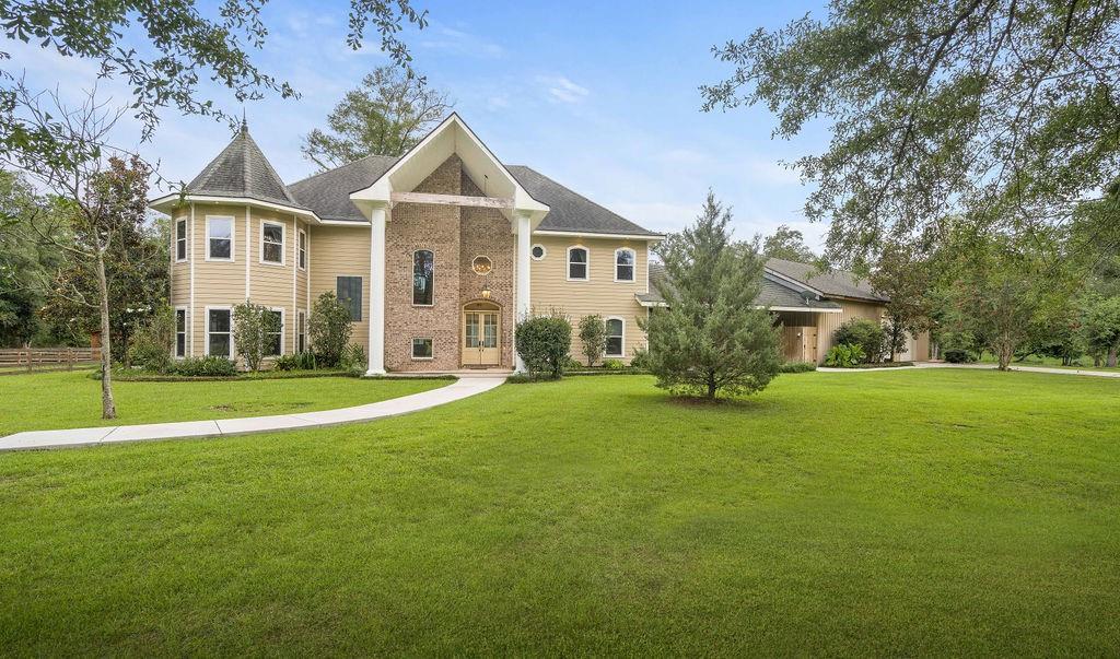 Two-story home with a brick entry, turret, broad lawn, and detached garage.