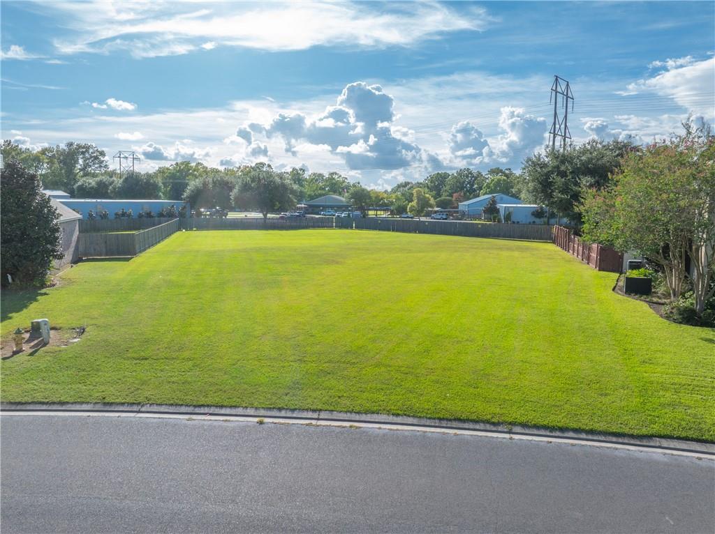 Aerial view of a broad grassy lot bordered by fencing and a road.