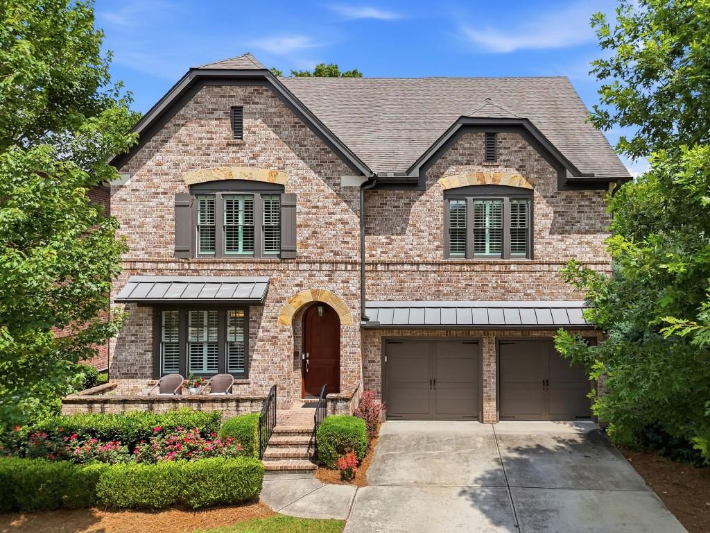 Two-story brick home with an arched entry, two-car garage, and landscaped front garden.