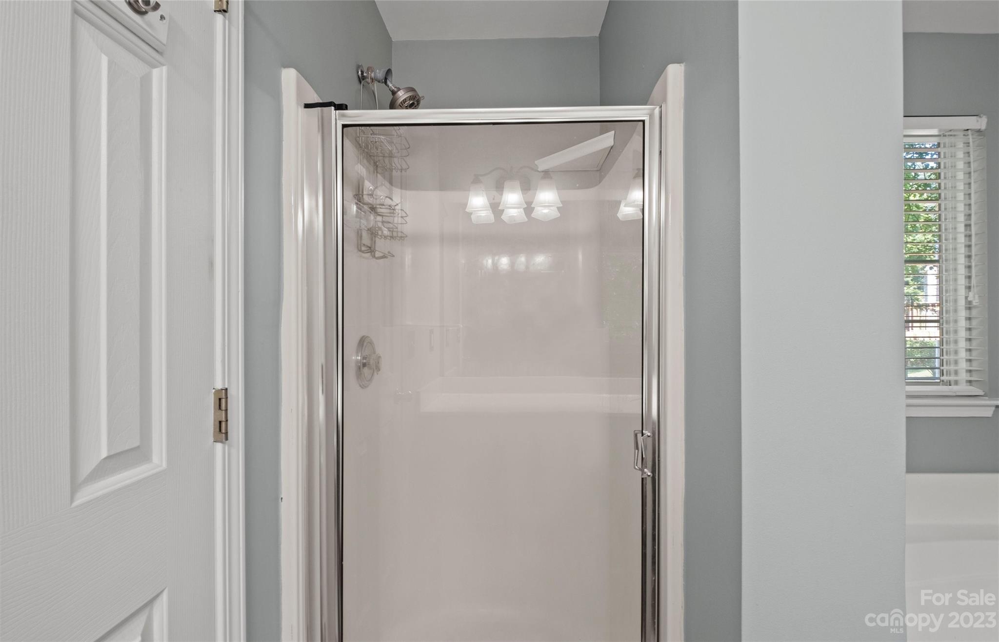 Bathroom shower with a glass enclosure, chrome fixtures, and built-in wire caddies.