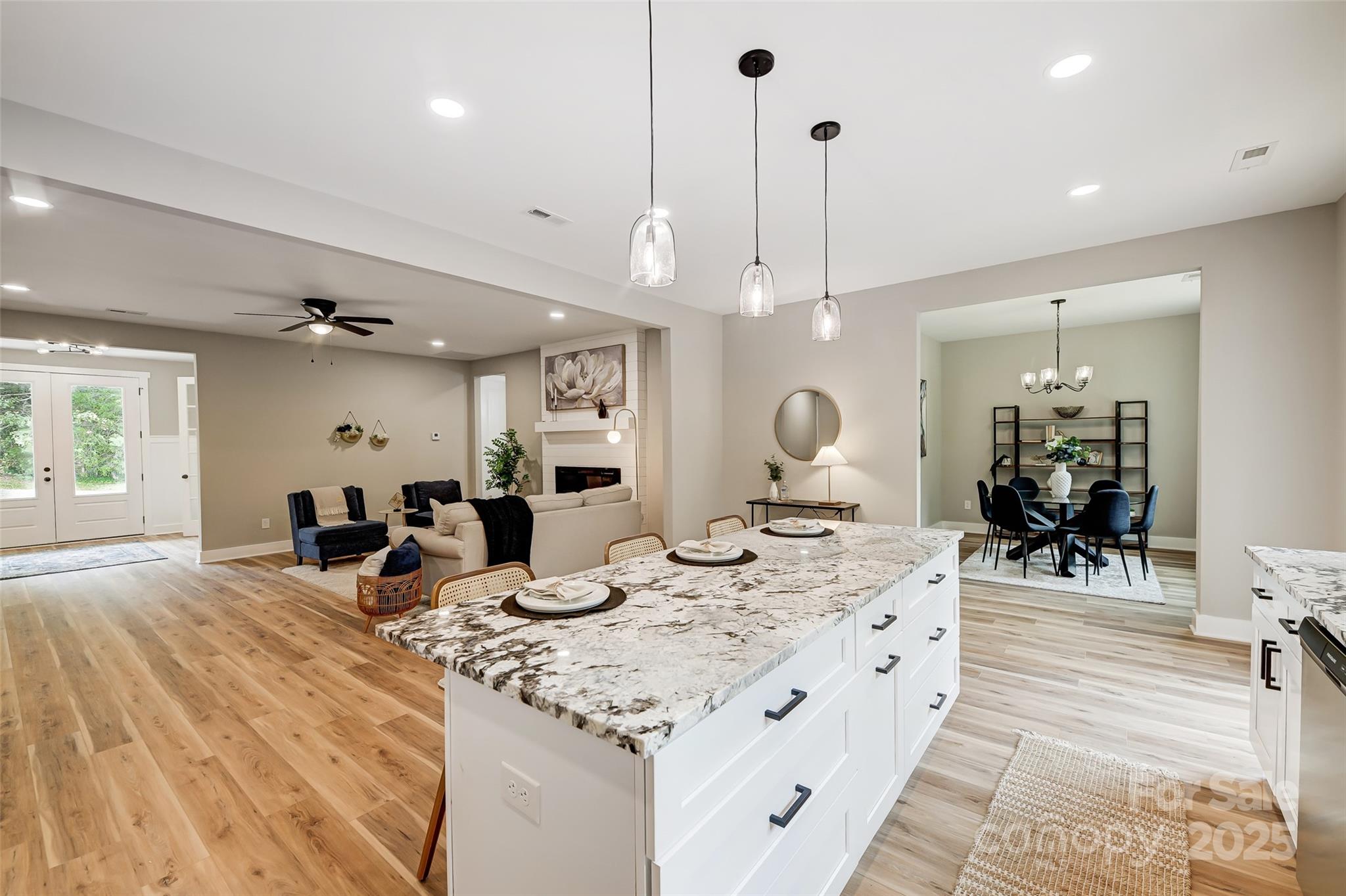 Open-plan kitchen with a large stone-topped island, adjoining living room, and dining area.