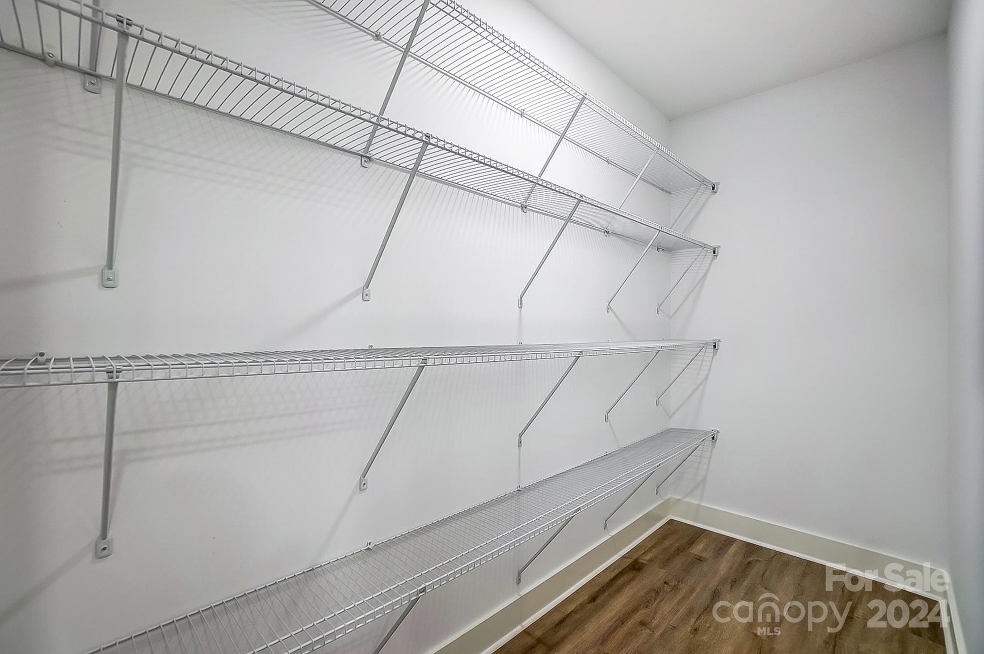 Walk-in closet with extensive wire shelving and wood-look flooring.