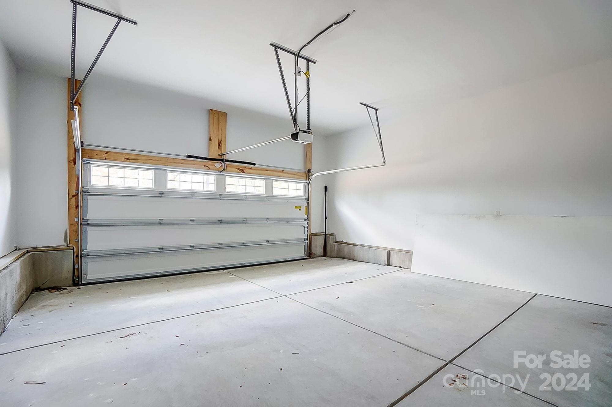 Empty garage with a concrete floor and closed windowed garage door.