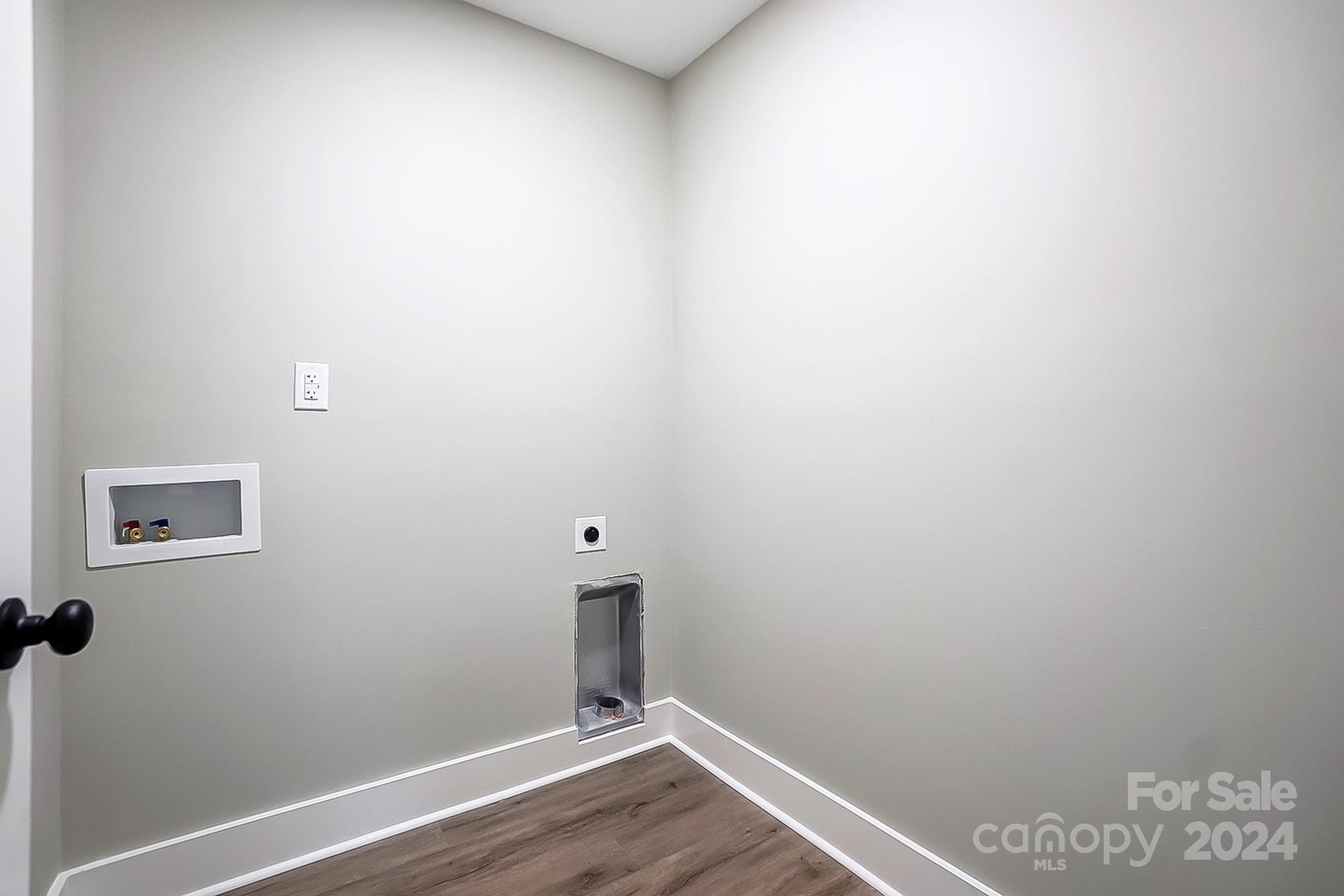 Empty laundry area with recessed red and blue water hookups and wall openings.
