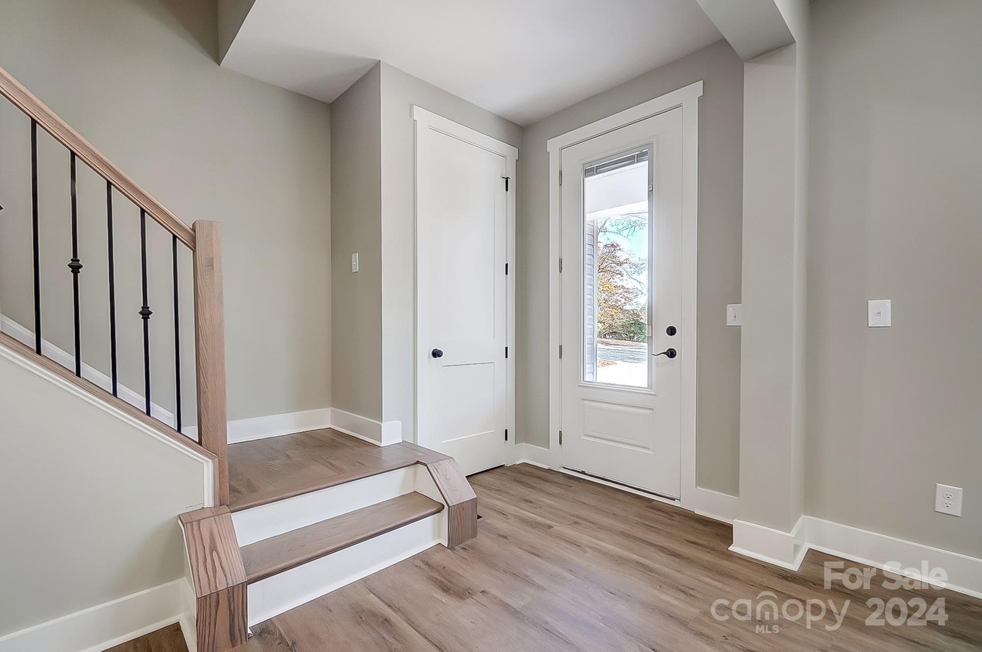 Entryway with a wood-floored staircase and white front door with a tall glass panel.