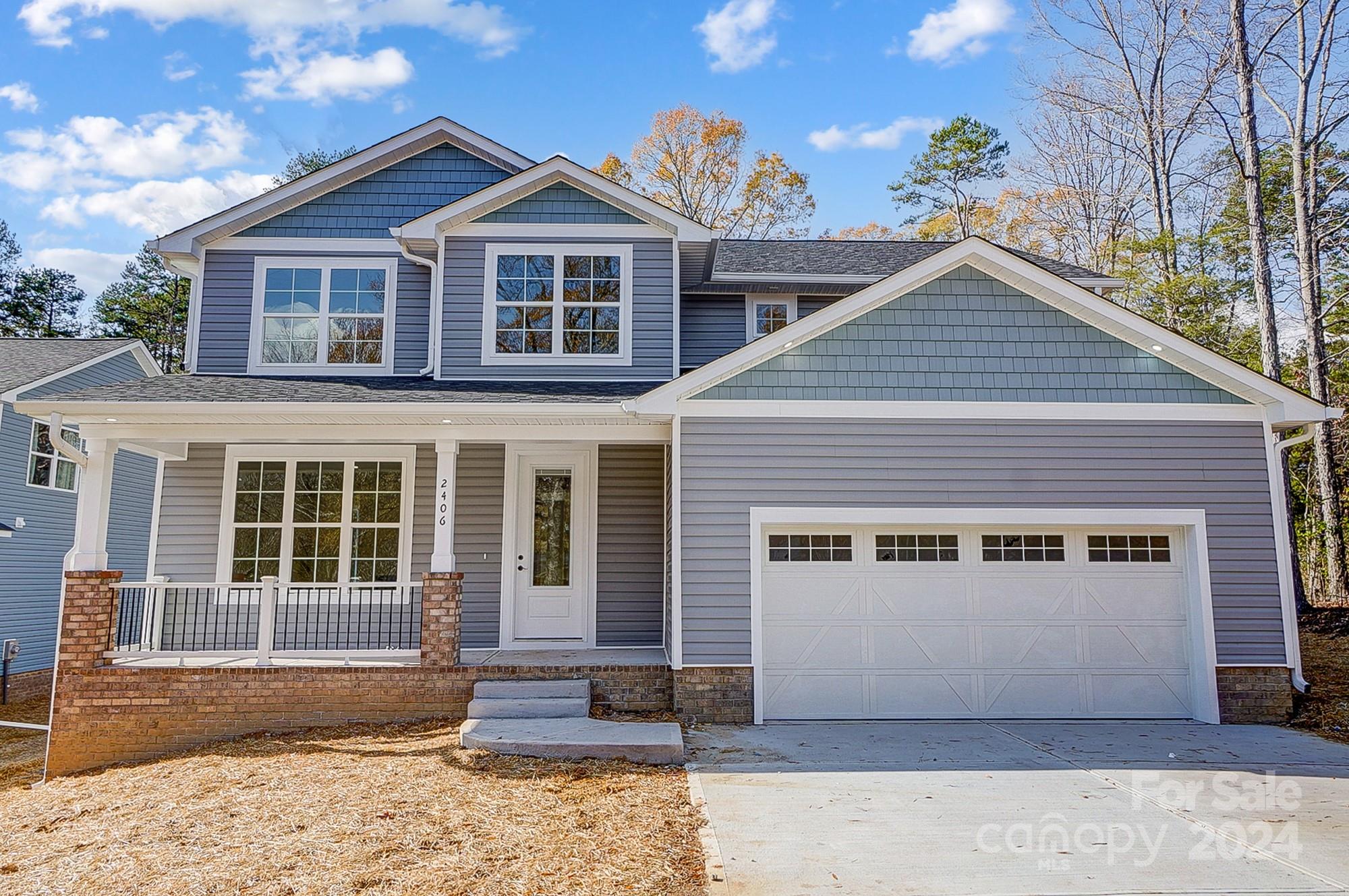 Two-story gray home with a covered porch, brick base, and attached two-car garage.
