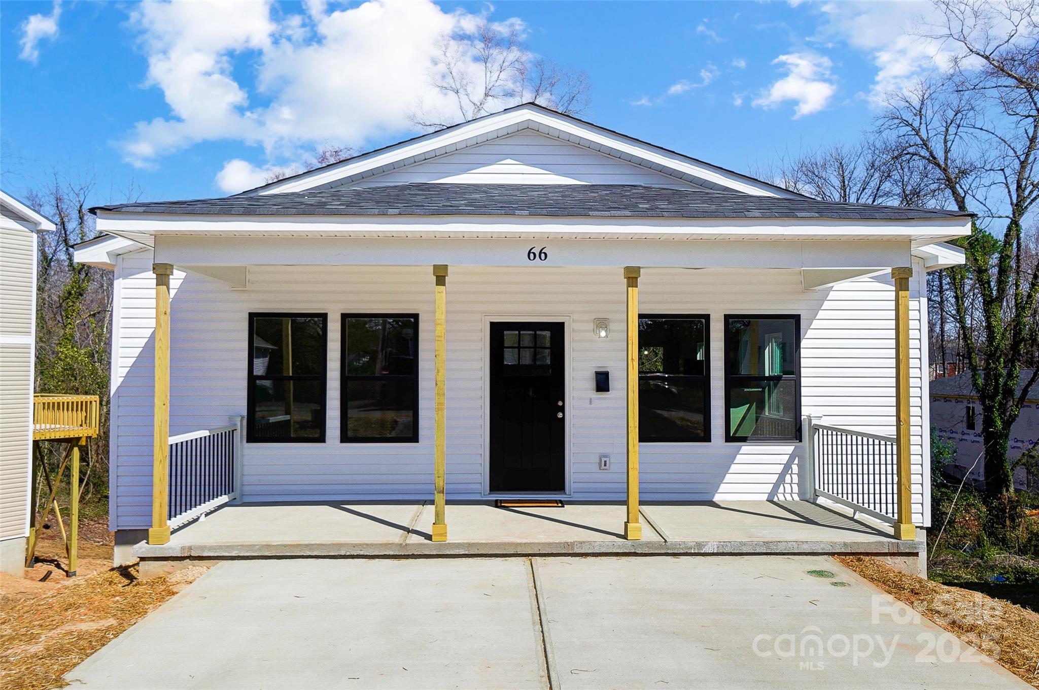 White house with a covered porch, black-framed windows, and a wide concrete driveway.