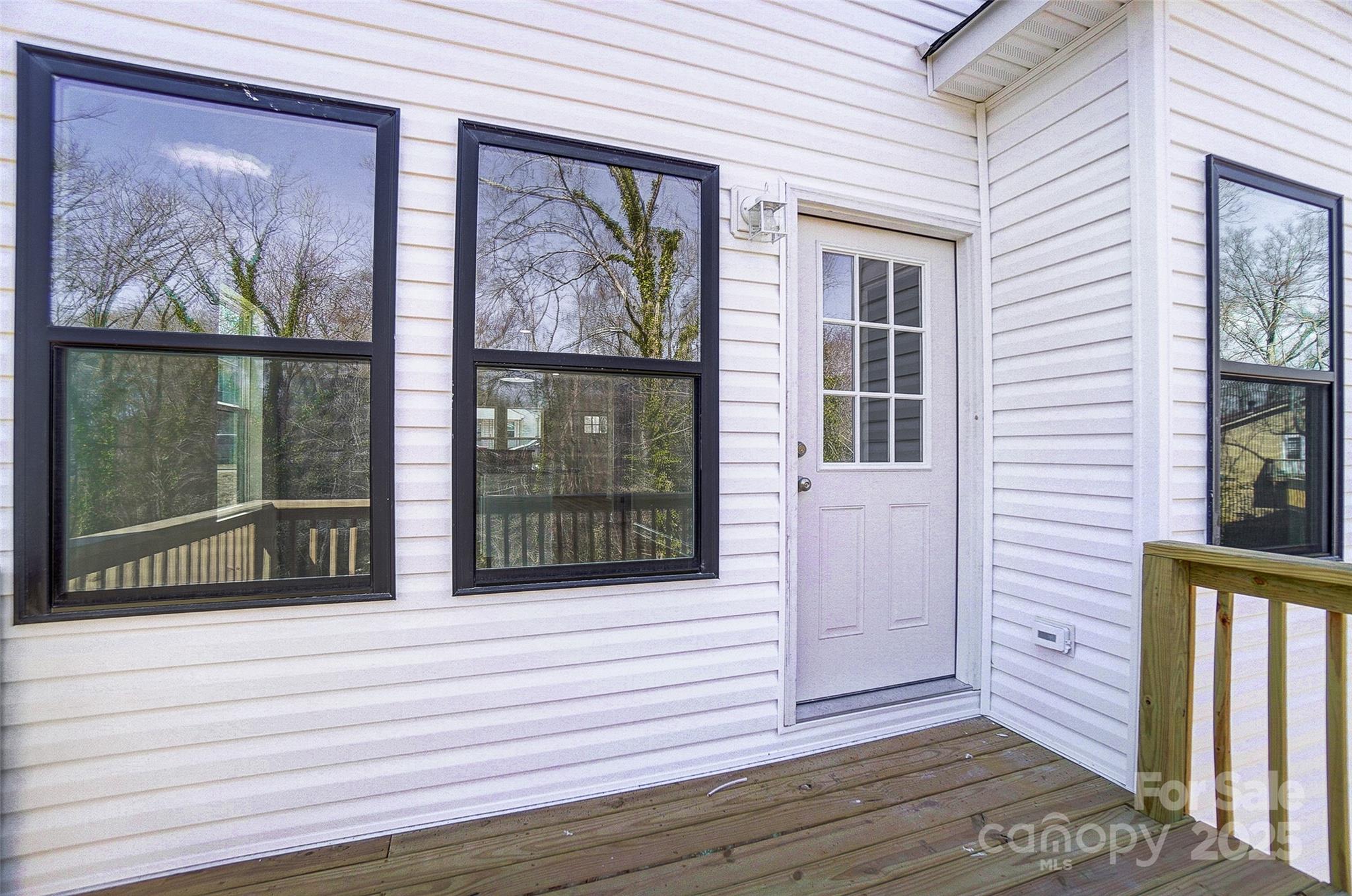 White back door and dark-framed windows opening onto a wooden deck.