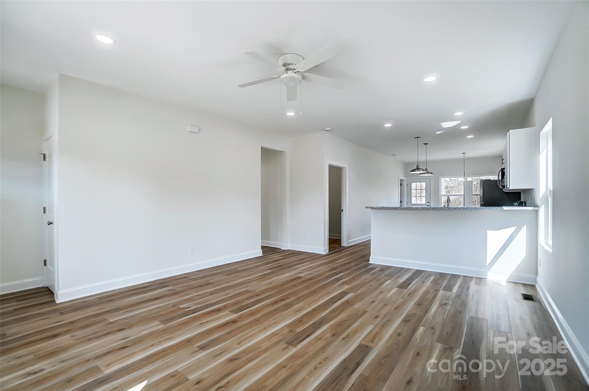 Open-plan living and dining area with wood-look floors and a kitchen peninsula.
