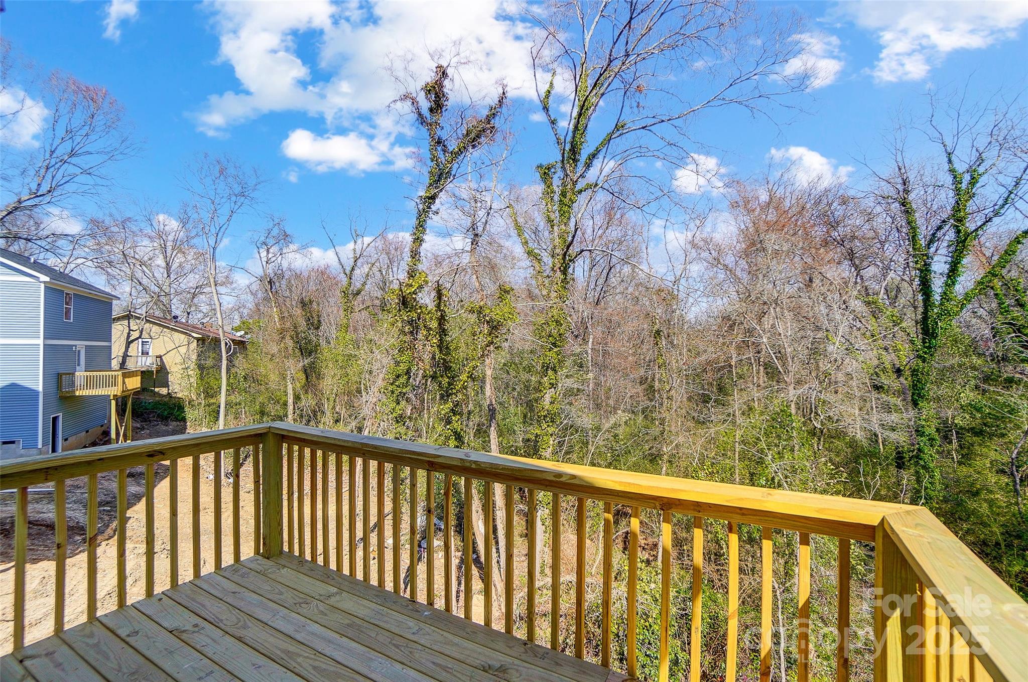 Wooden rear deck overlooking a wooded backyard and neighboring homes.