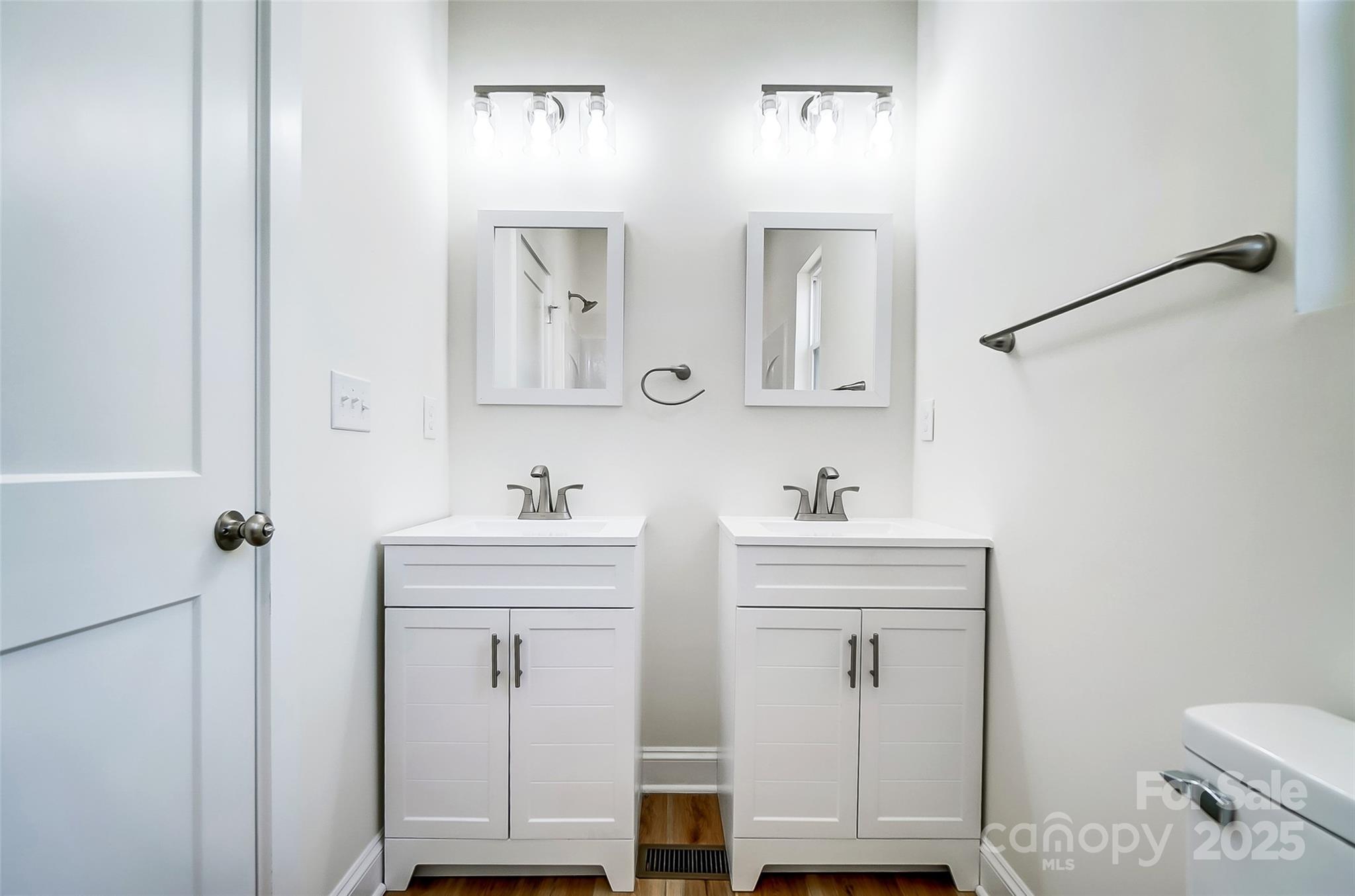 Bathroom with double white vanities, framed mirrors, and a wall-mounted grab bar.