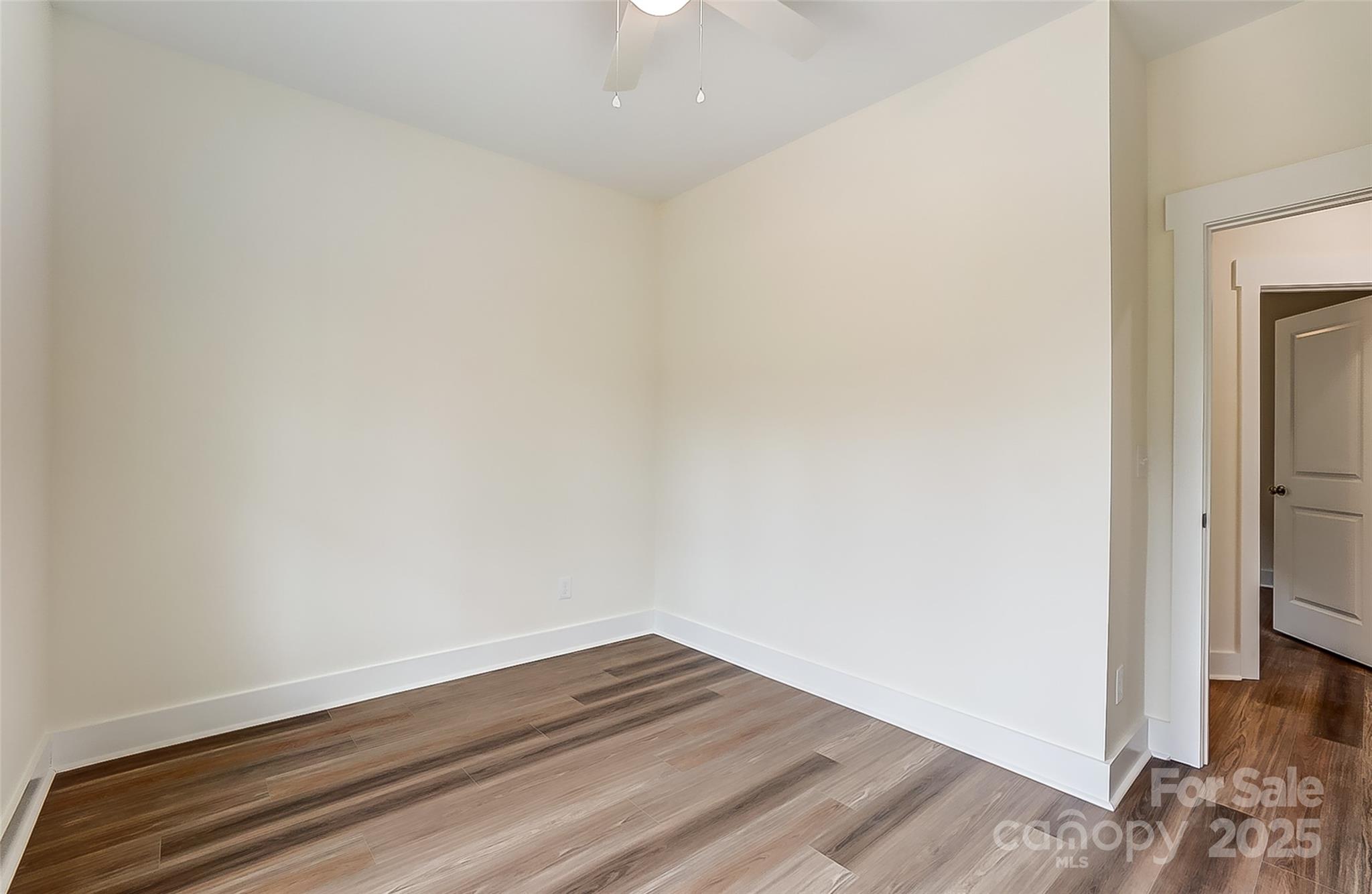 Empty room with wood-look plank flooring, white walls, and an open doorway.
