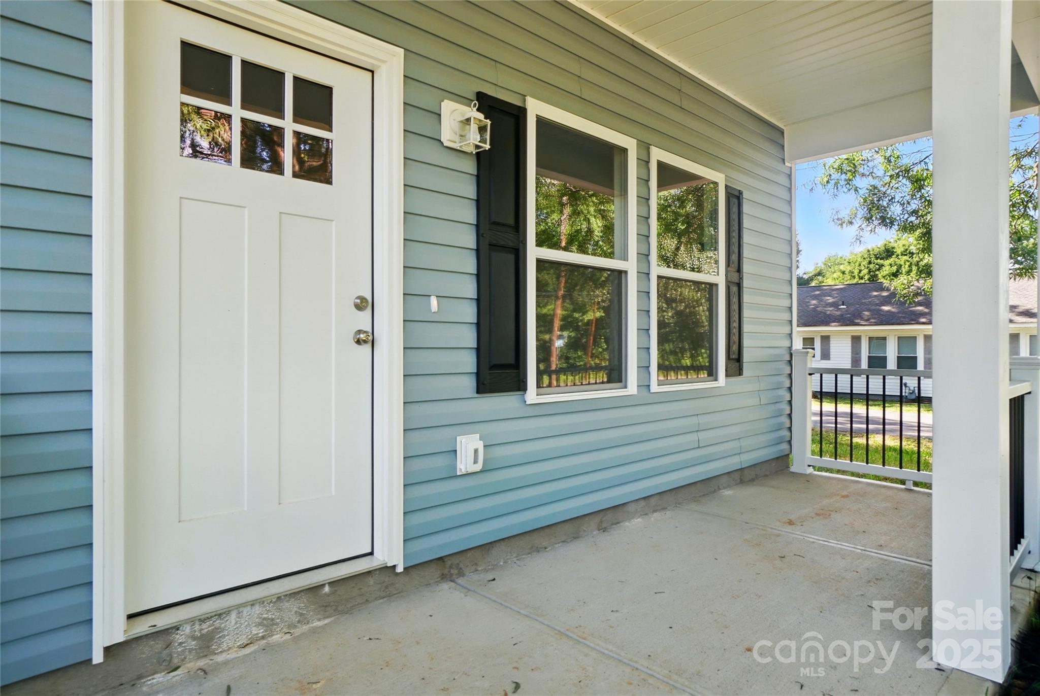Covered porch with blue siding, white entry door, and black-shuttered windows.