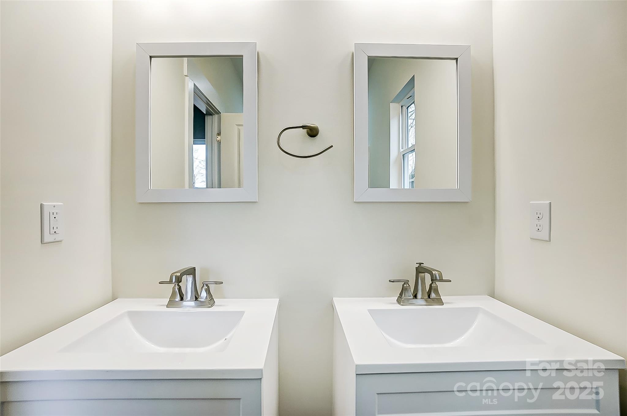 Bathroom with double white vanities, chrome faucets, and matching rectangular mirrors.