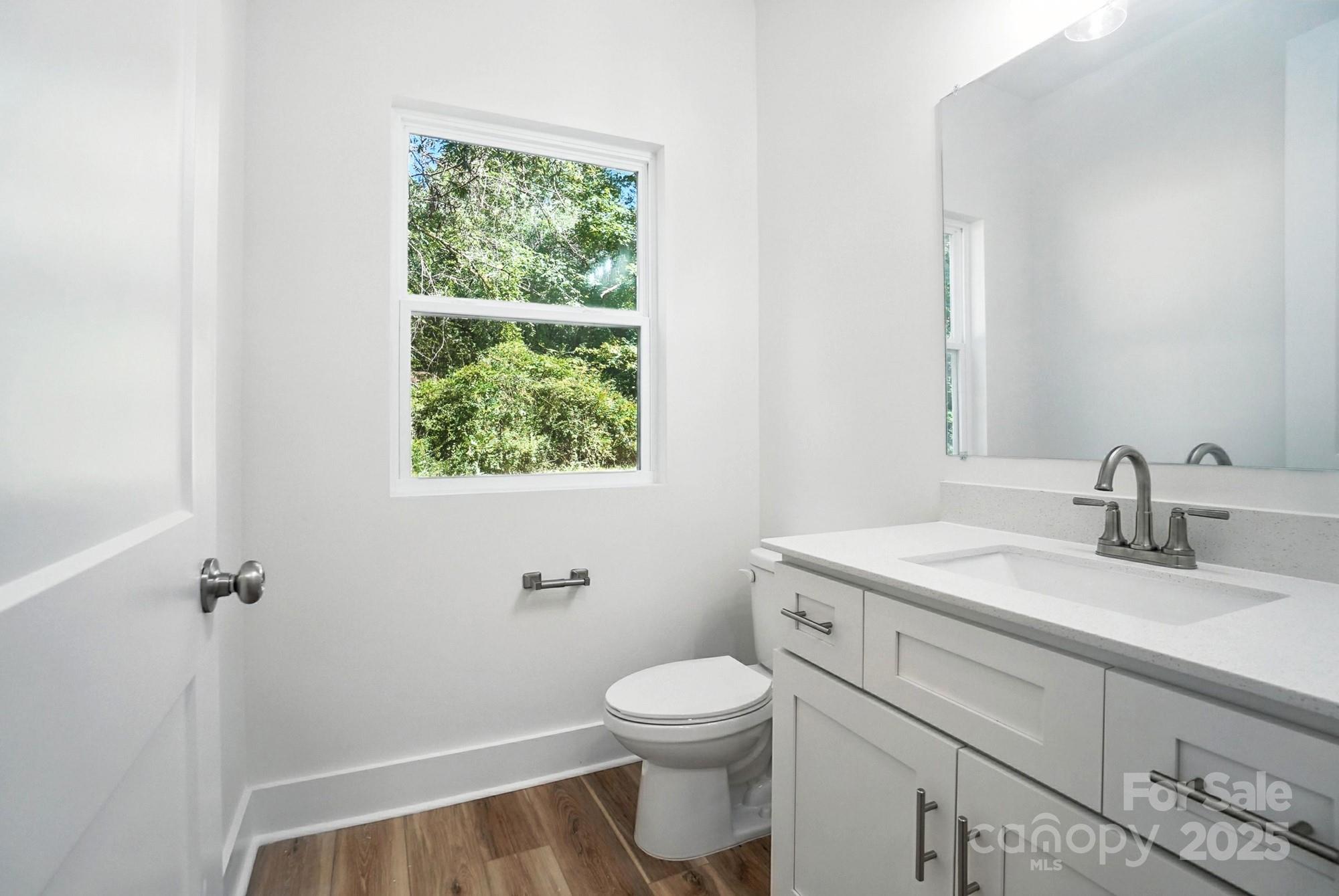 Bright bathroom with a white vanity and large window overlooking greenery.