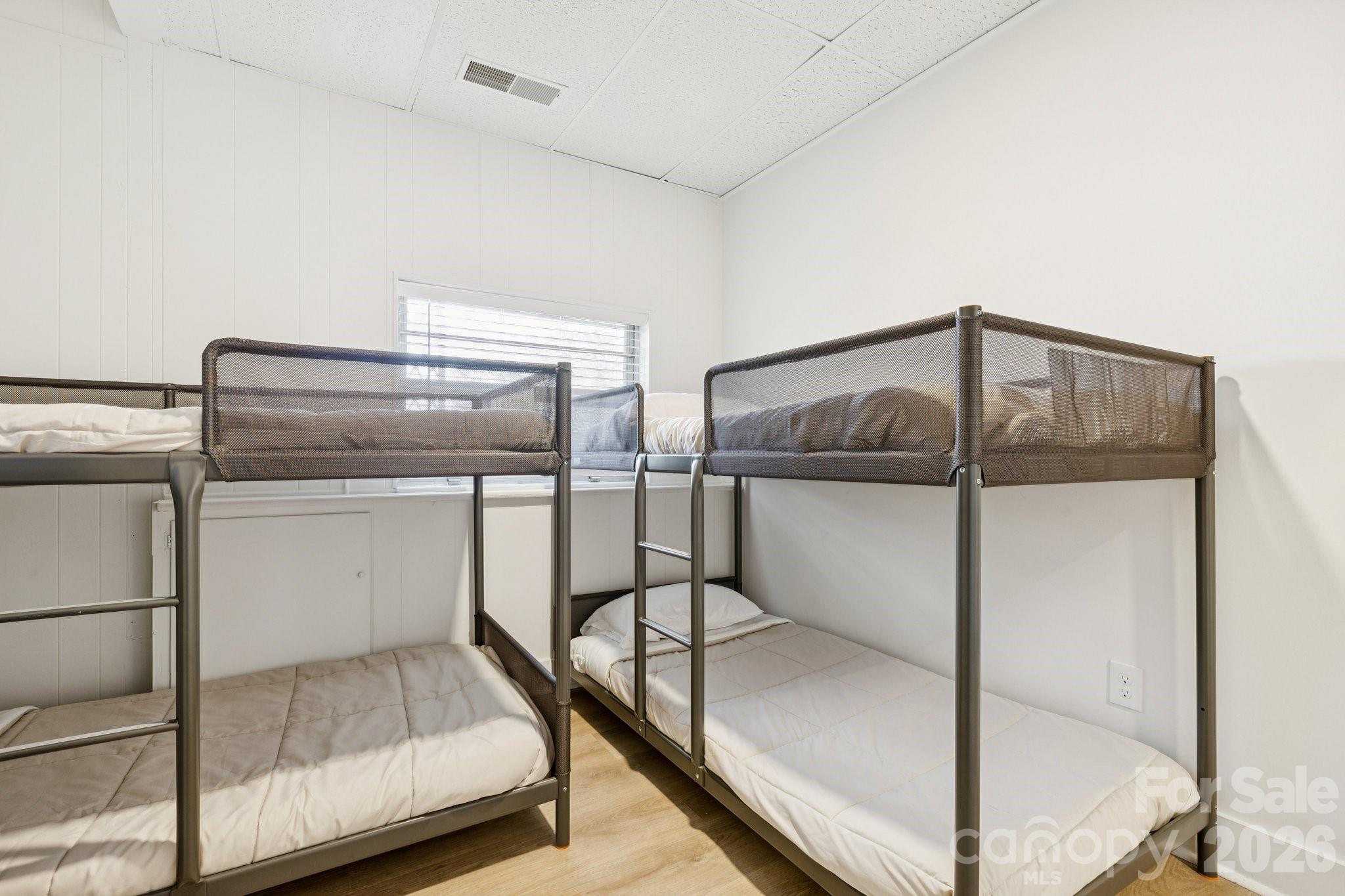 Bedroom furnished with multiple metal bunk beds and white bedding.