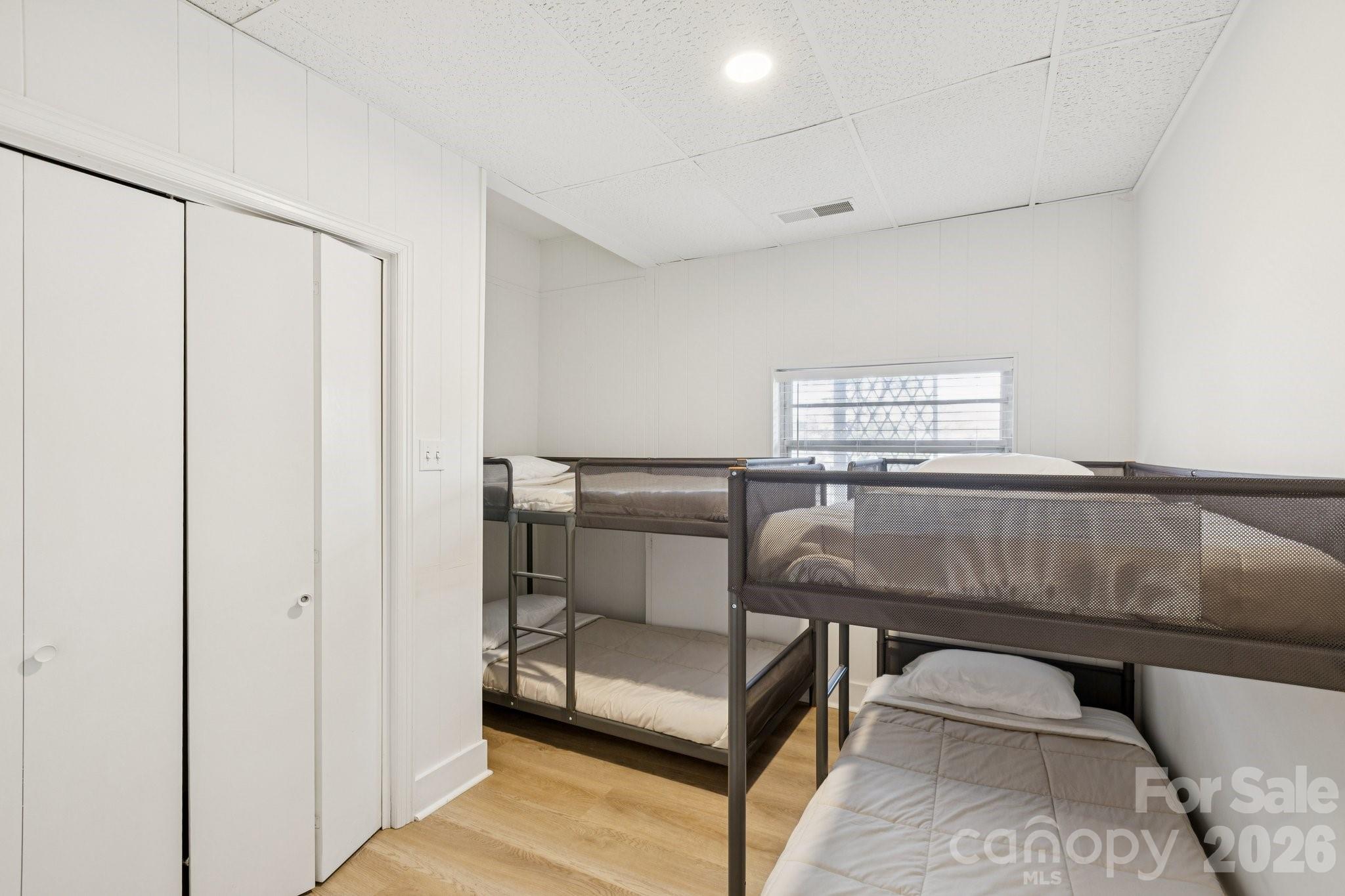 Bedroom with multiple metal bunk beds and a window with blinds.