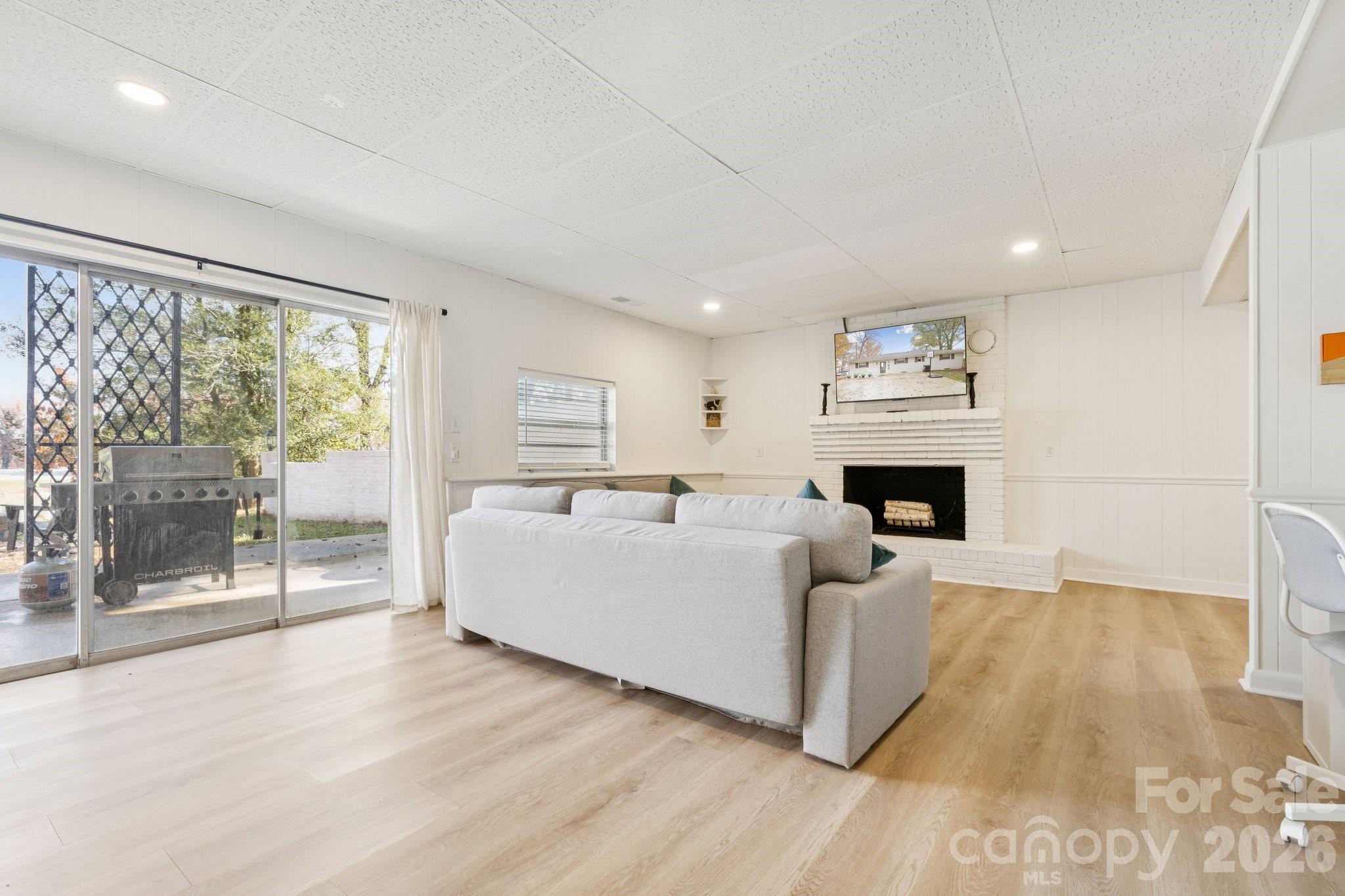 Living room with a white brick fireplace, gray sectional, and sliding glass doors to a patio.