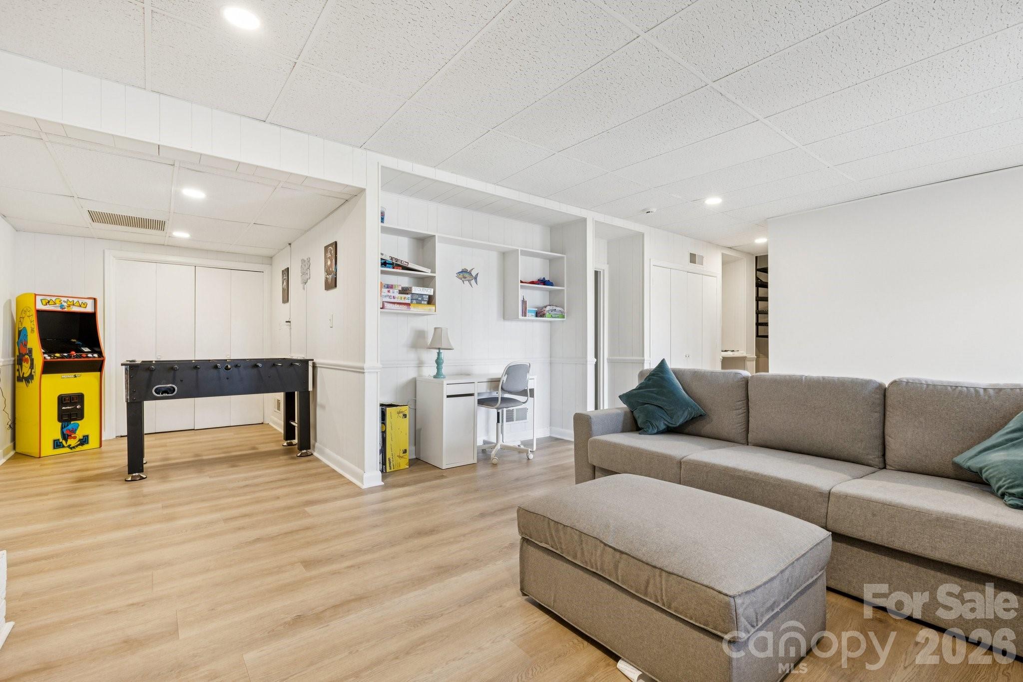 Recreation room with a sectional, foosball table, Pac-Man arcade cabinet, and built-in desk.