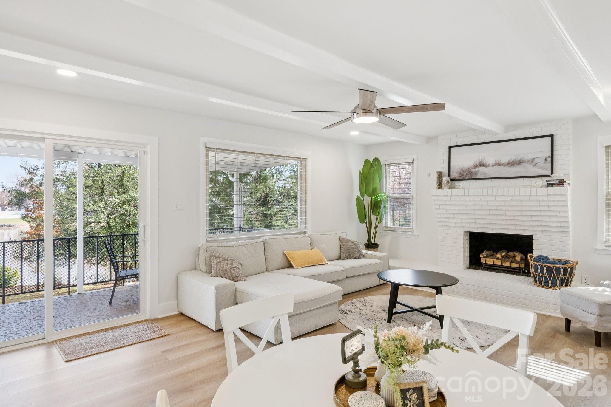 Living room with a white brick fireplace, large sectional, and sliding doors opening toward the water.