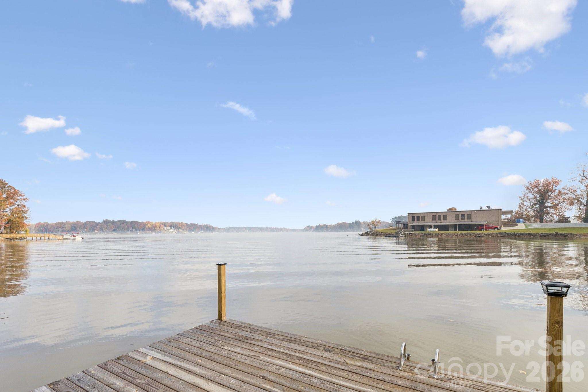 Lake viewed from a wooden dock with a swim ladder and autumn trees along the far shore.