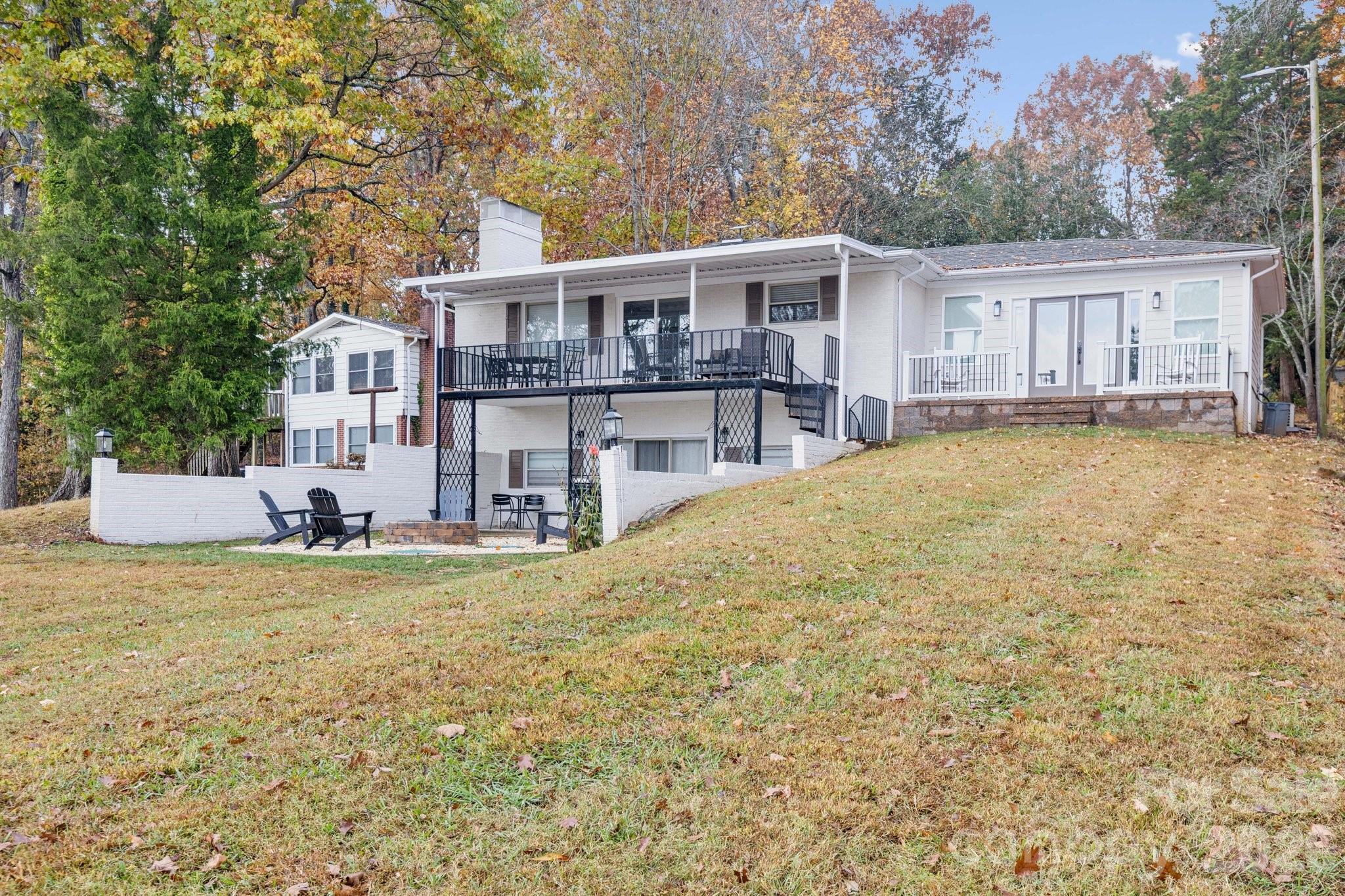 White split-level home with a covered raised deck and lower patio on a sloping lawn.