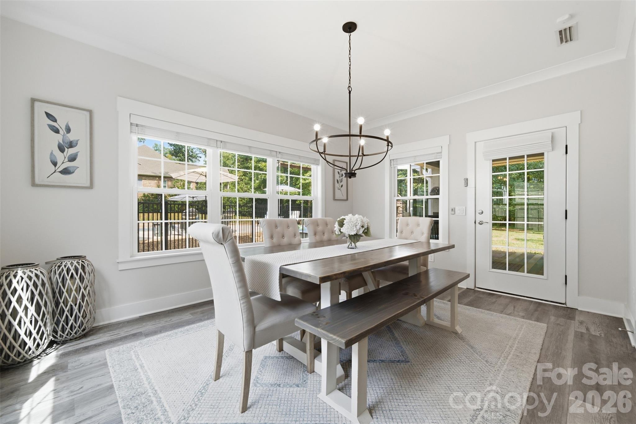 Dining room with a long wood table, upholstered seating, and large windows overlooking the yard.