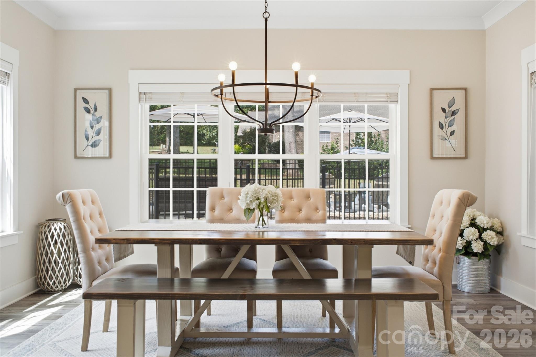 Staged dining room with a long wood table, upholstered chairs, and large windows overlooking a patio.