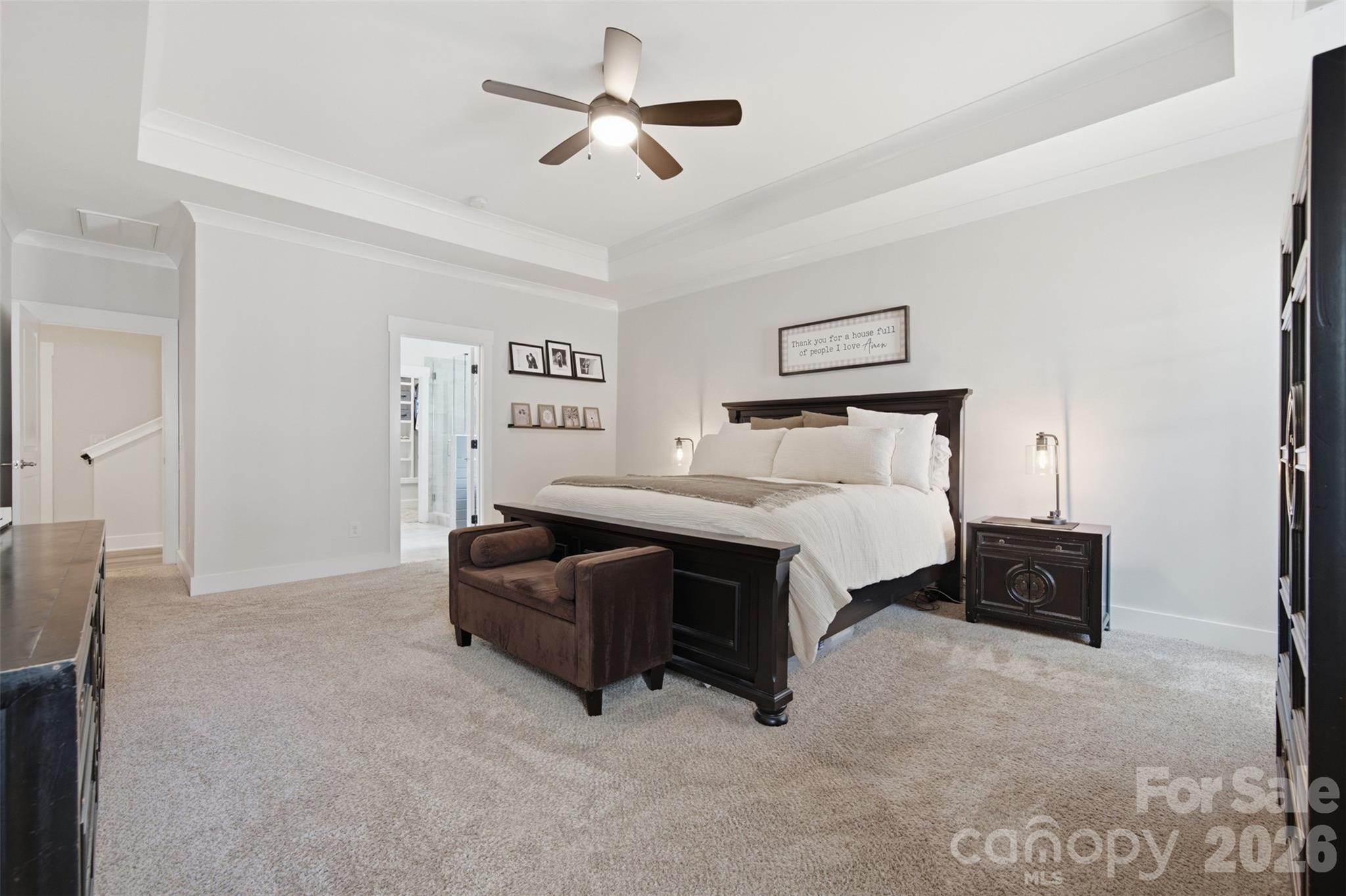 Furnished bedroom with a dark wood bed, white bedding, brown bench, and beige carpet.