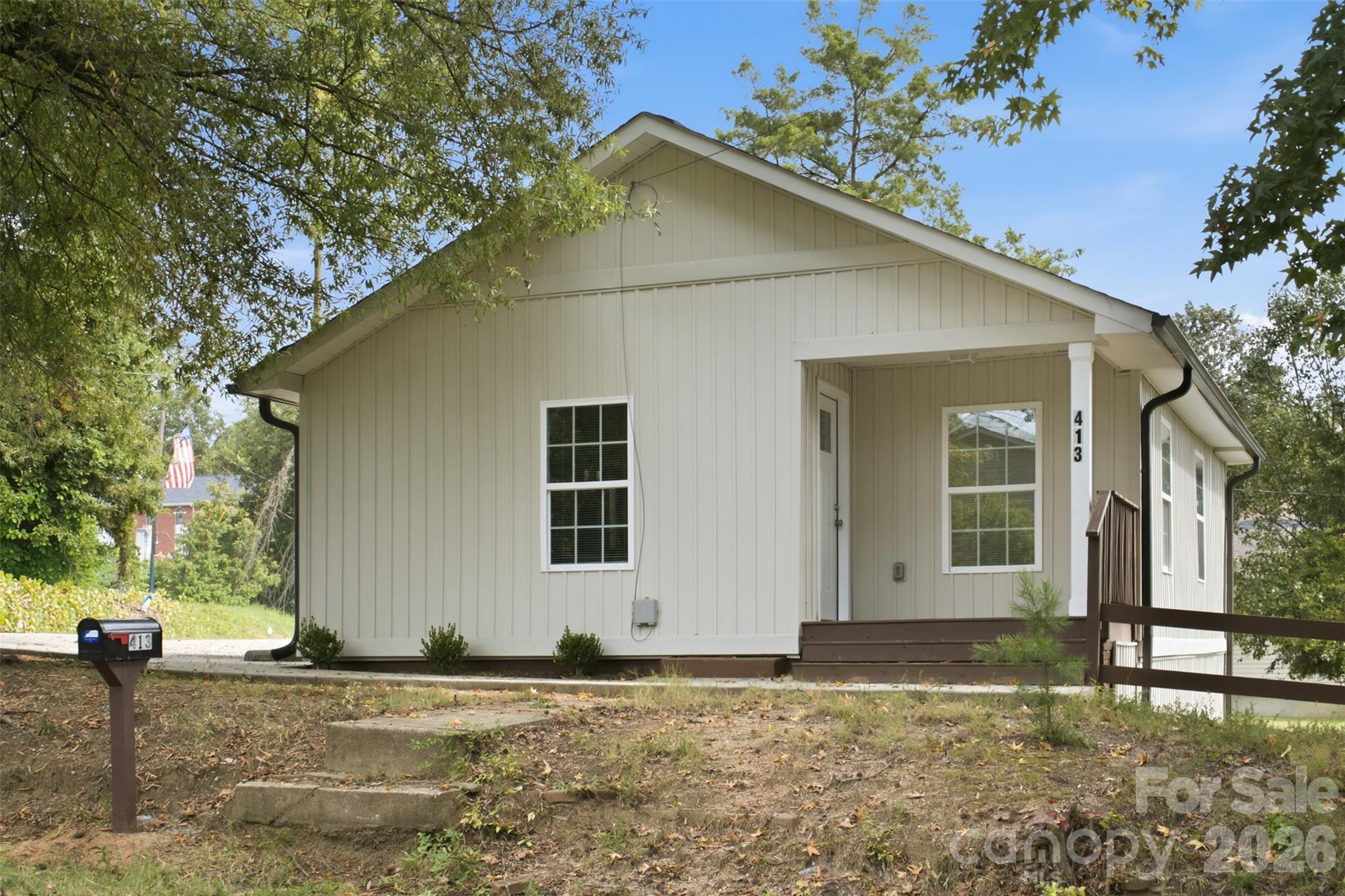 White-sided house with a covered porch, brown steps, and a mailbox marked 413.