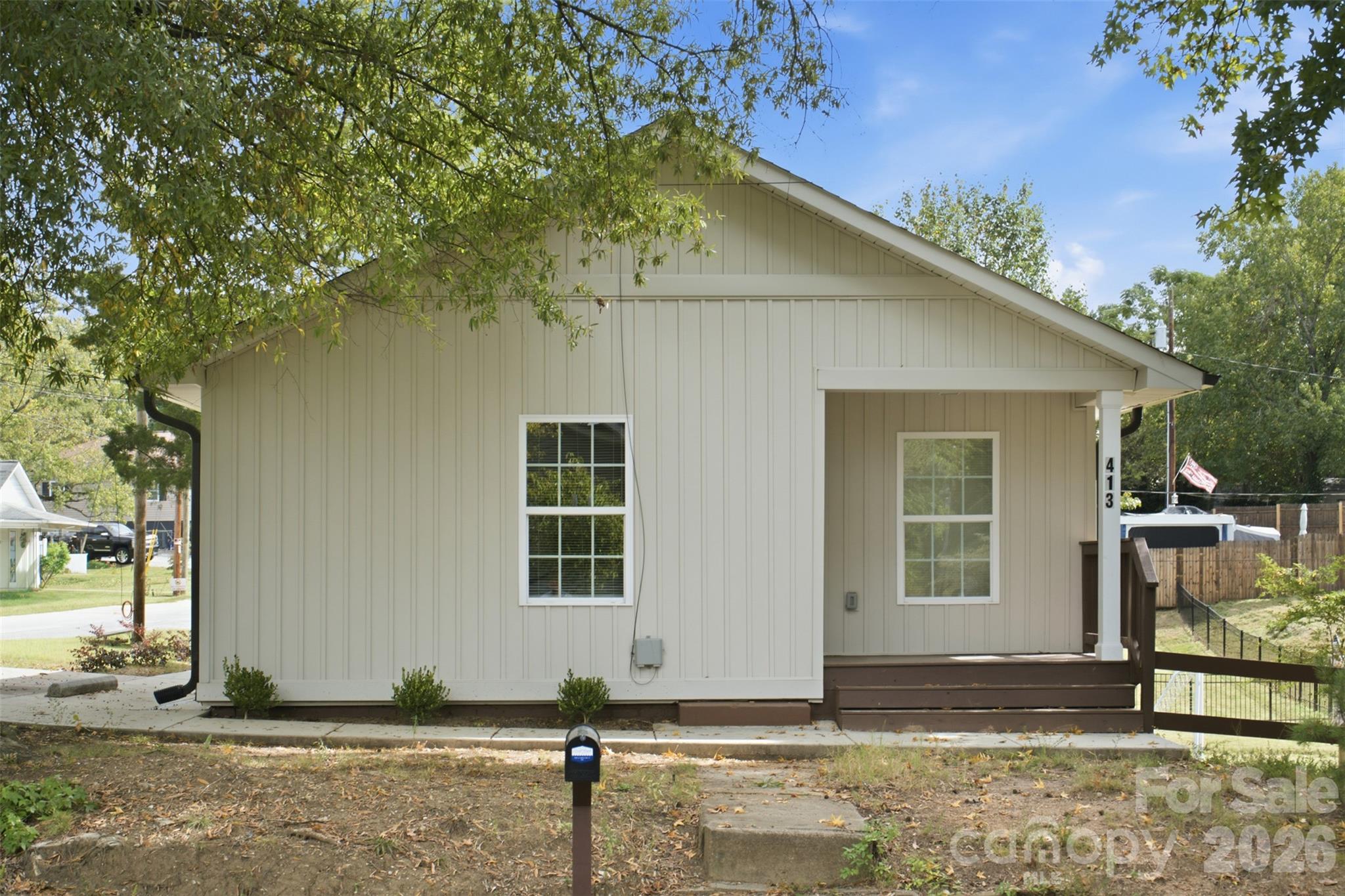 Light-colored house with a covered porch, brown steps, and address 413 on the porch post.